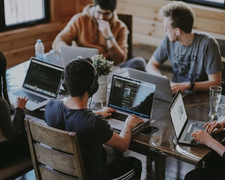 Three people working on computers in an office environment.