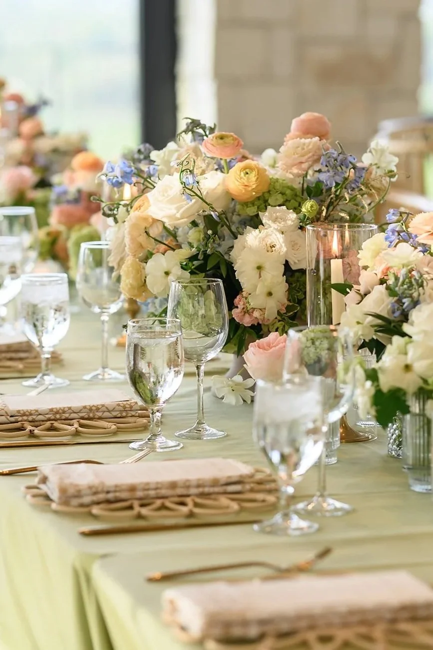 Elegant table setting with floral centerpiece, candle, glassware, and napkins at a wedding or special event.
