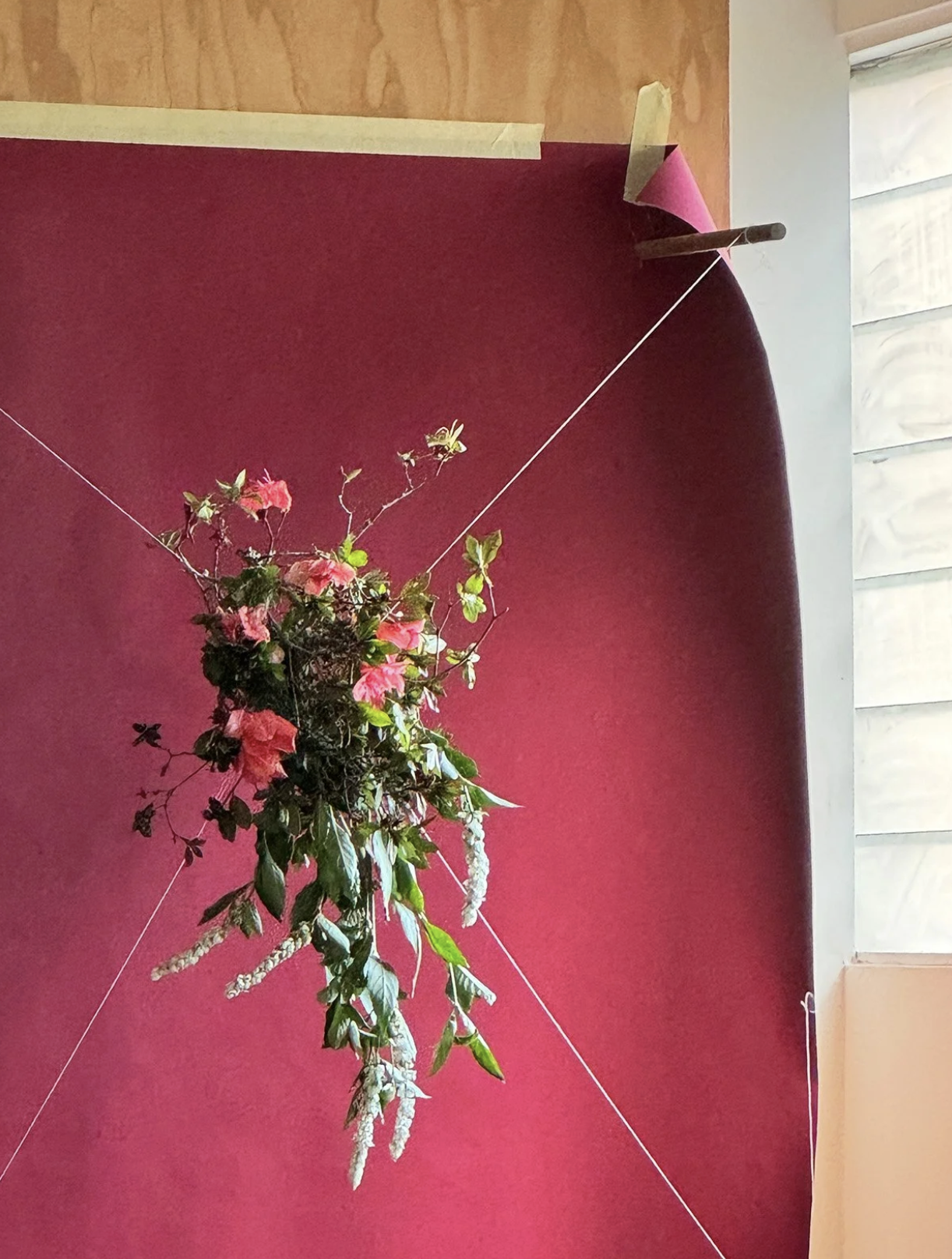 hanging azalea flowers and leaves strung by string on a red backdrop