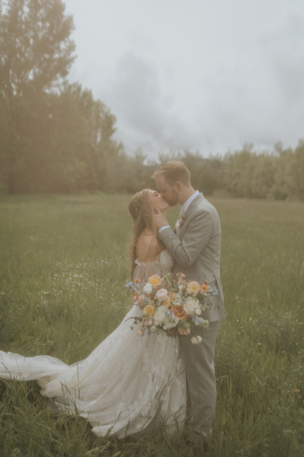 Plume&Furrow-Wedding-Florist-theMandinos-AbbyRindelPhoto-LoneHawk-Farm-Colorado-June-bride-groom-kiss-vintage-field-bouquet.jpg