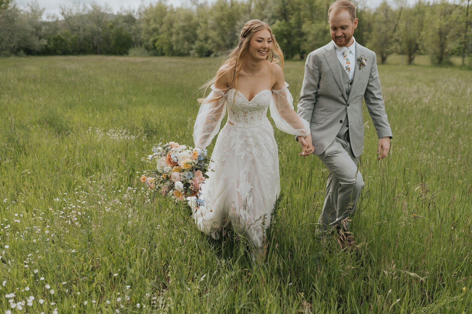 Plume&Furrow-Wedding-Florist-theMandinos-AbbyRindelPhoto-LoneHawk-Farm-Colorado-June-bride-groom-holding-hands-in-field-with-bouquet.jpg