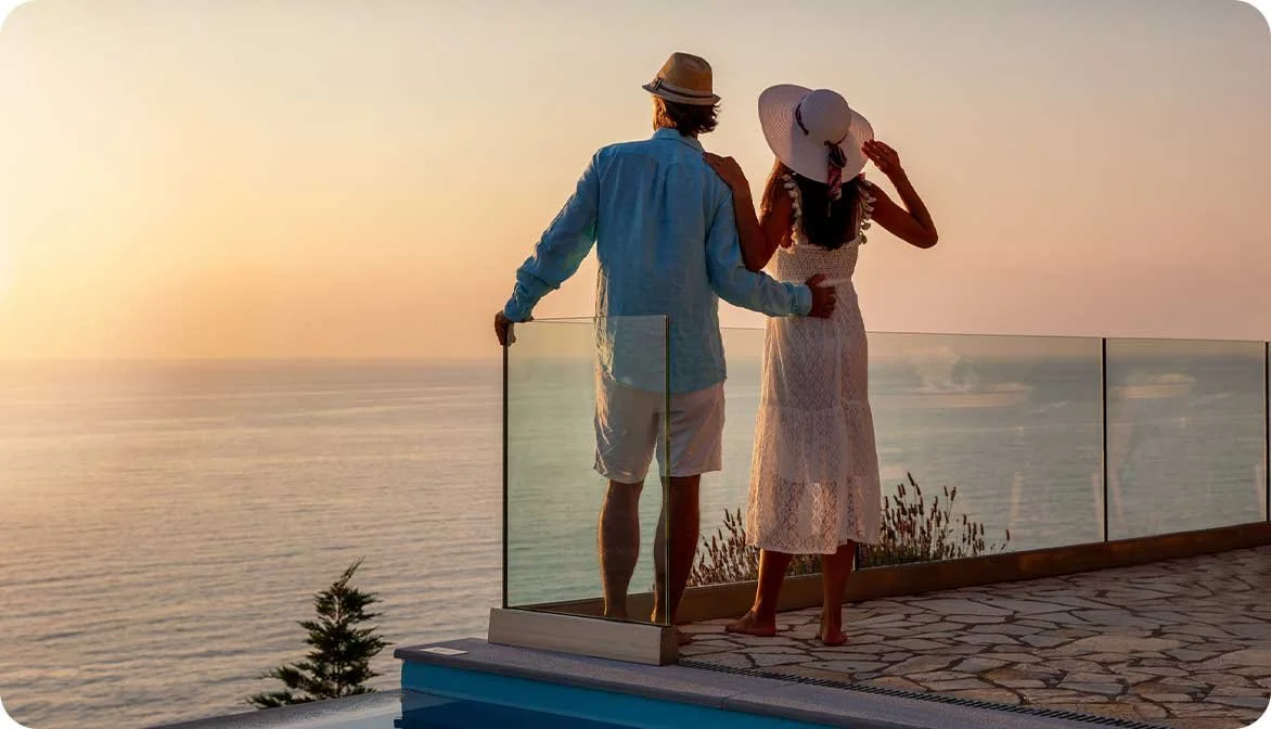 A couple enjoying a sunset view from a luxury hotel room balcony, representing how properties use experience-led hospitality to drive premium ancillary revenue.