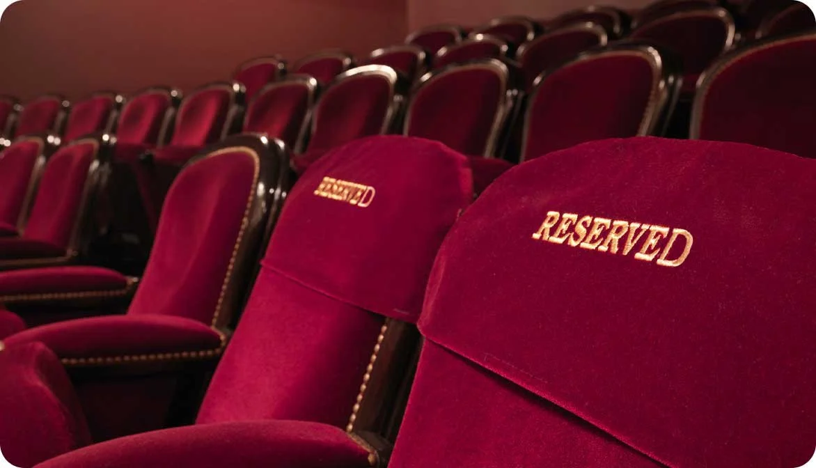 A row of empty auditorium seats with a reserved message sign on them, illustrating how travel operators use unit-level availability to manage capacity and inventory constraints