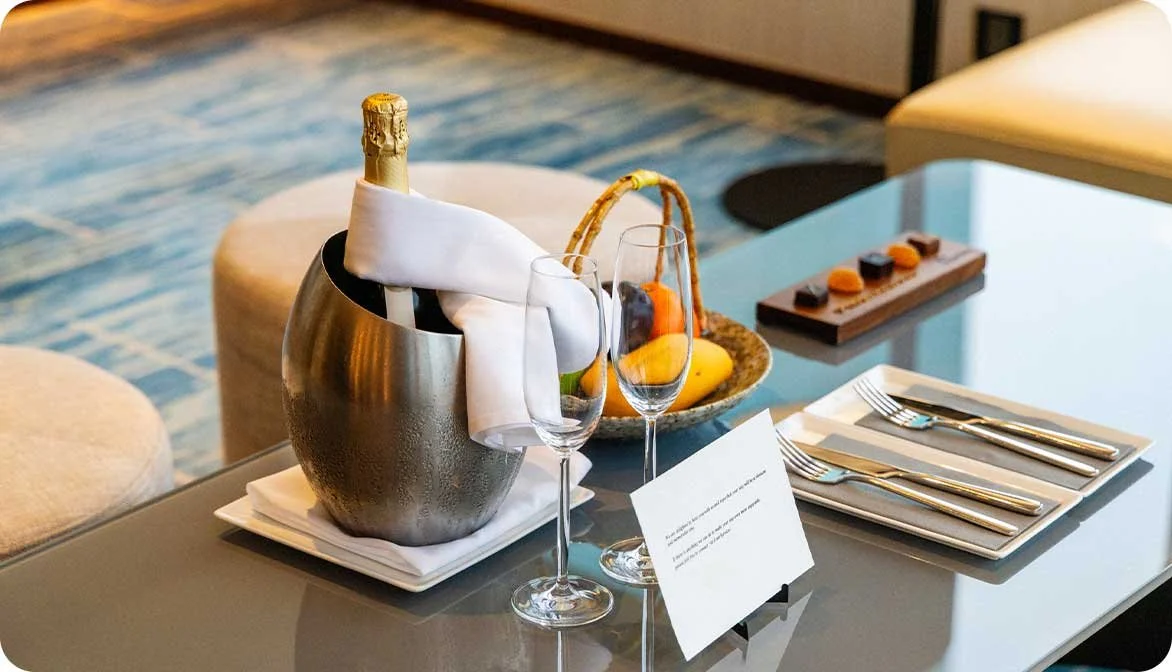 A luxury hotel room welcome tray featuring champagne glasses and a personalized card, illustrating how properties monetize premium amenities and bookable VIP spaces.