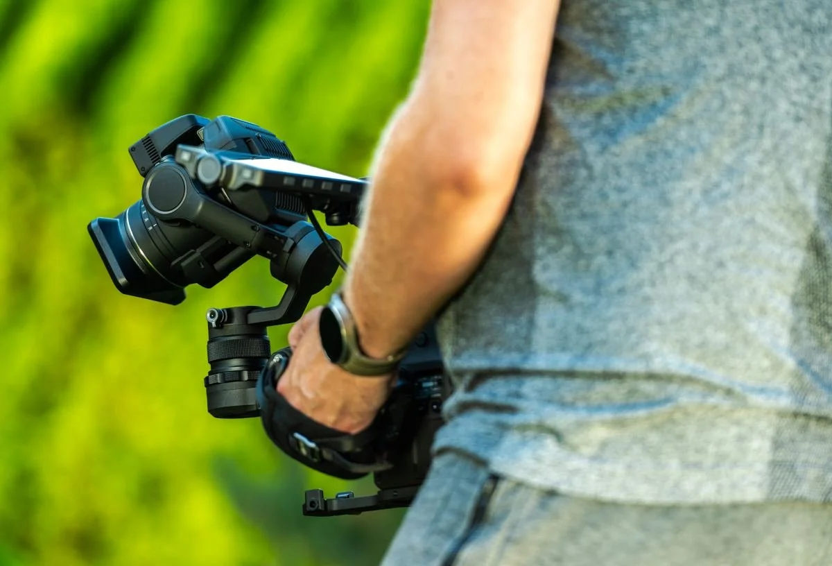 Filmmaker Capturing Outdoor Footage With Camera Gear During Golden Hour in a Natural Setting