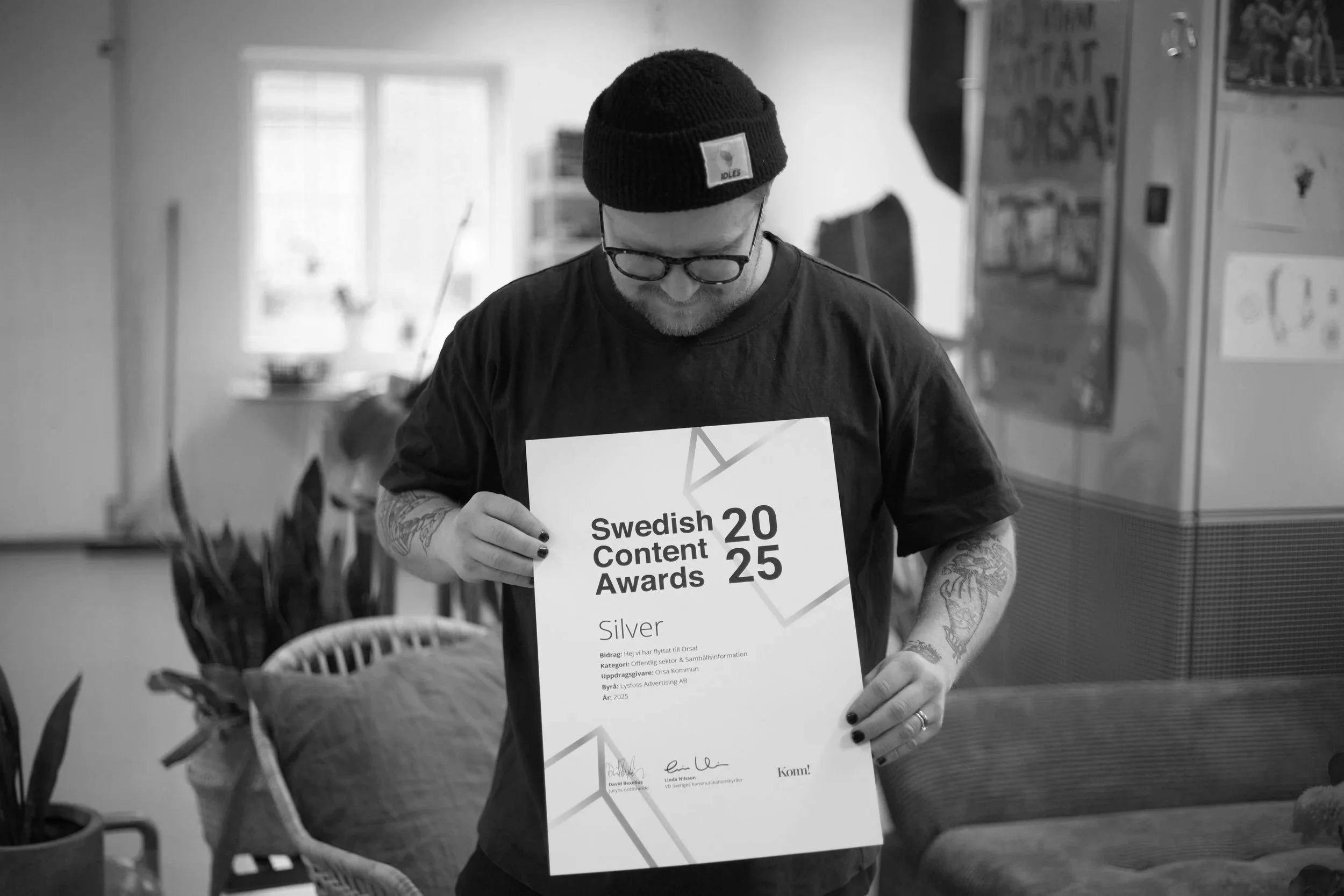 En ung man med svart mössa, glasögon och tatueringar håller i ett svartvitt diplom från Swedish Content Awards 2025.