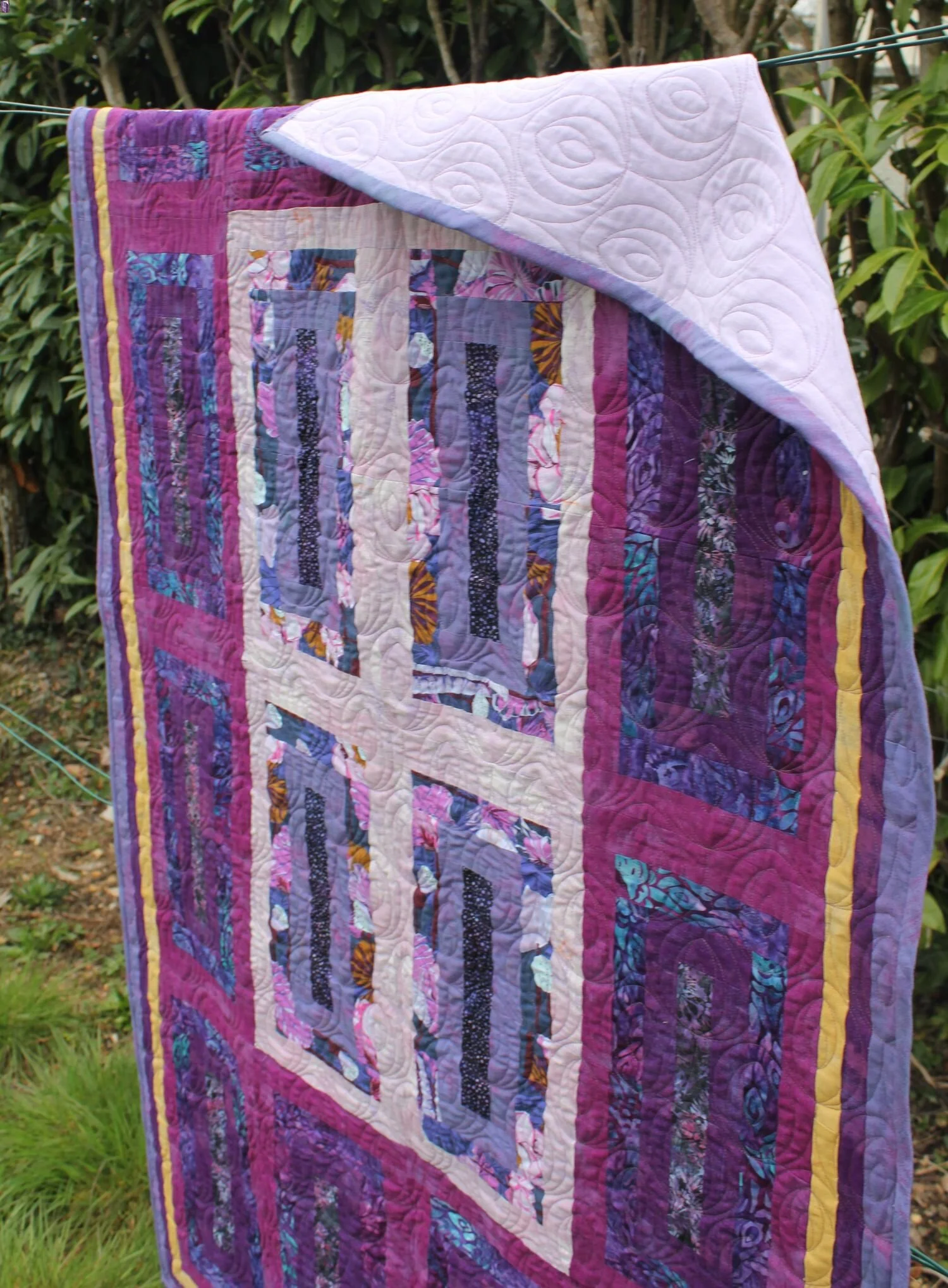 Jeté de canapé en violet et mauve pend sur une corde à linge.