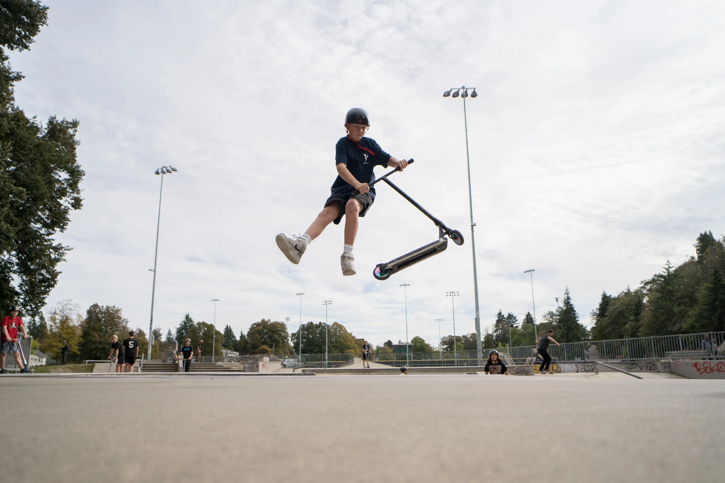 A skater takes a scooter up a ramp at the Lower Woodland Skate Park.