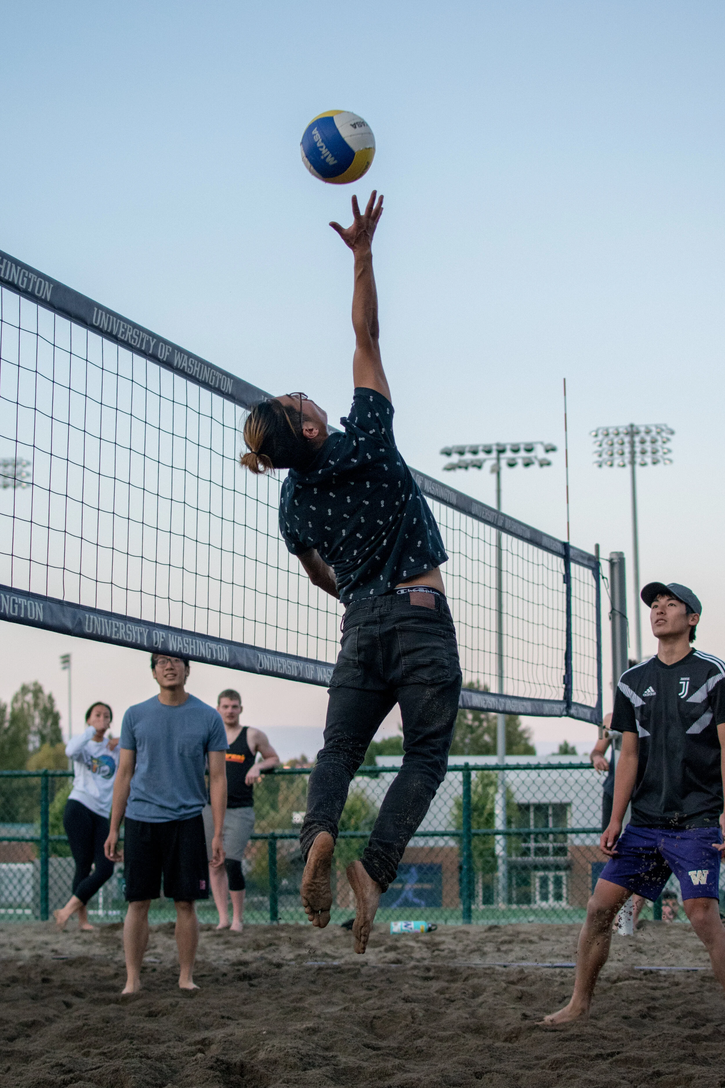 Nathan Narita goes up to deflect a volleyball at the University of Washington outdoor courts.