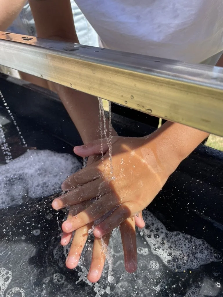 Hands being washed on an outdoor handwashing station