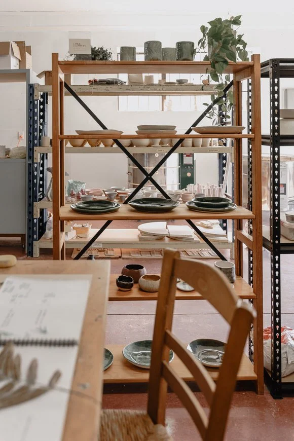 Wooden shelves with ceramic dishes and pottery in a workshop