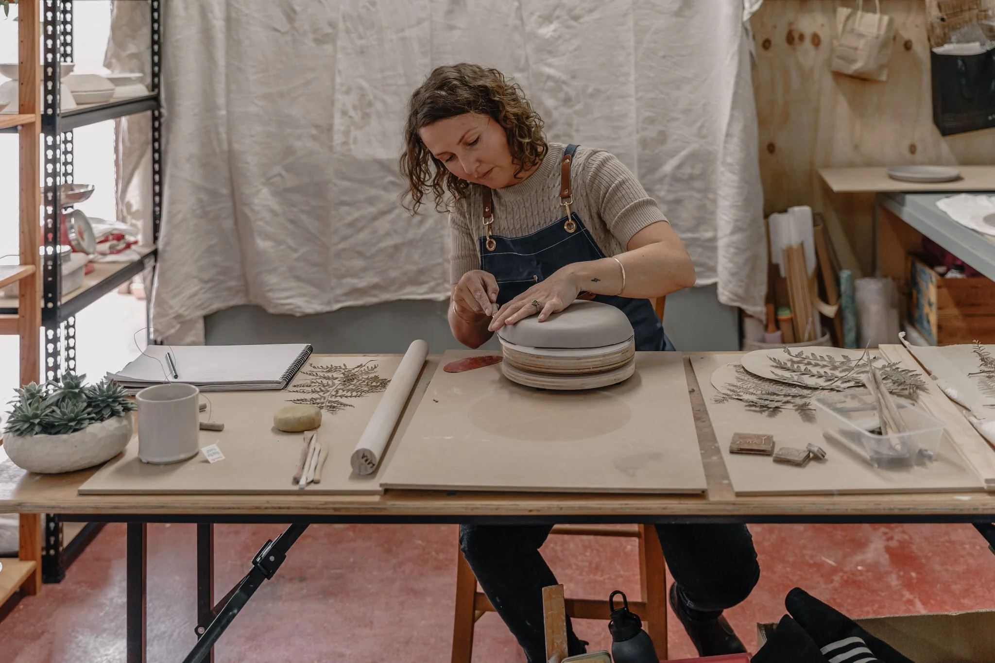 Woman working with clay at a pottery studio table