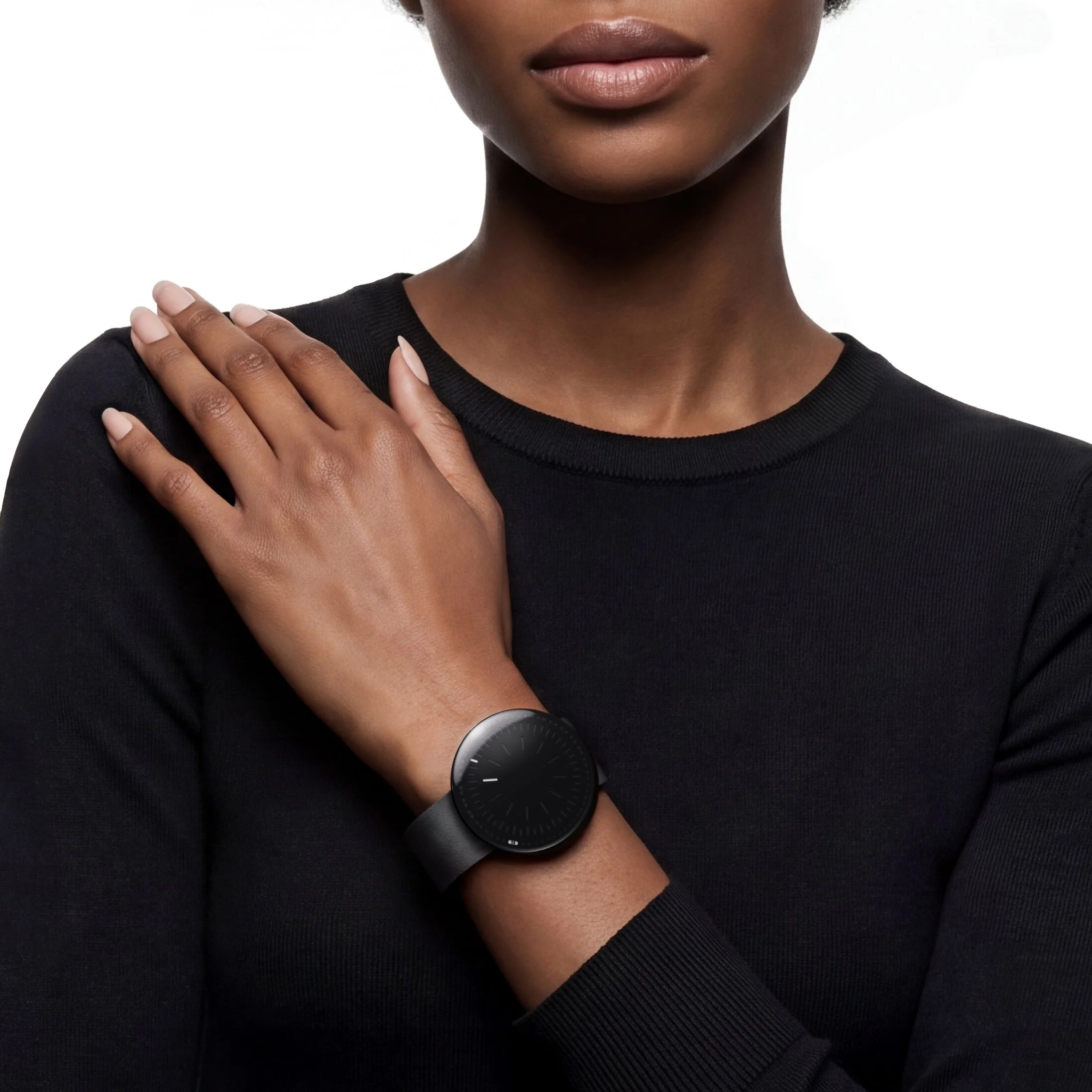 RVNDSGN watch with black dial and black leather strap on a womans wrist.