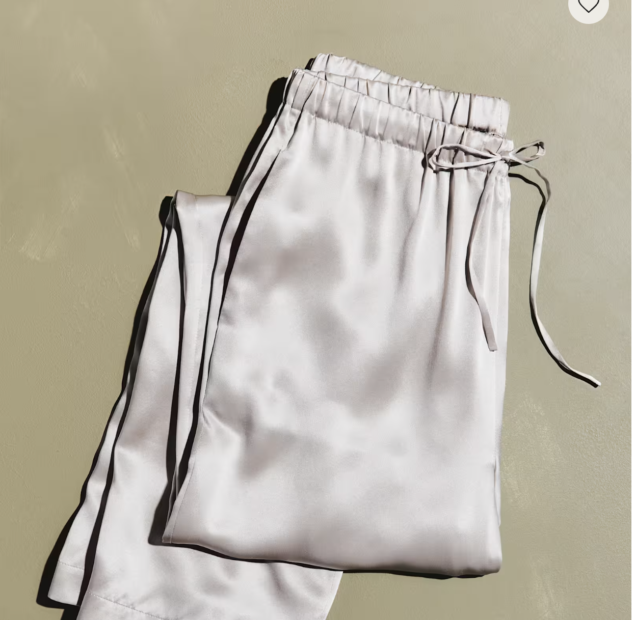 a pair of silk wide leg pants against a beige wall