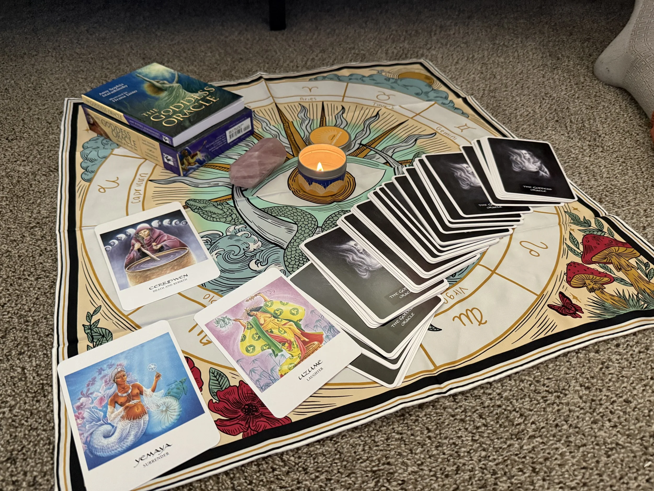 patterened scarf with oracle cards and a candle