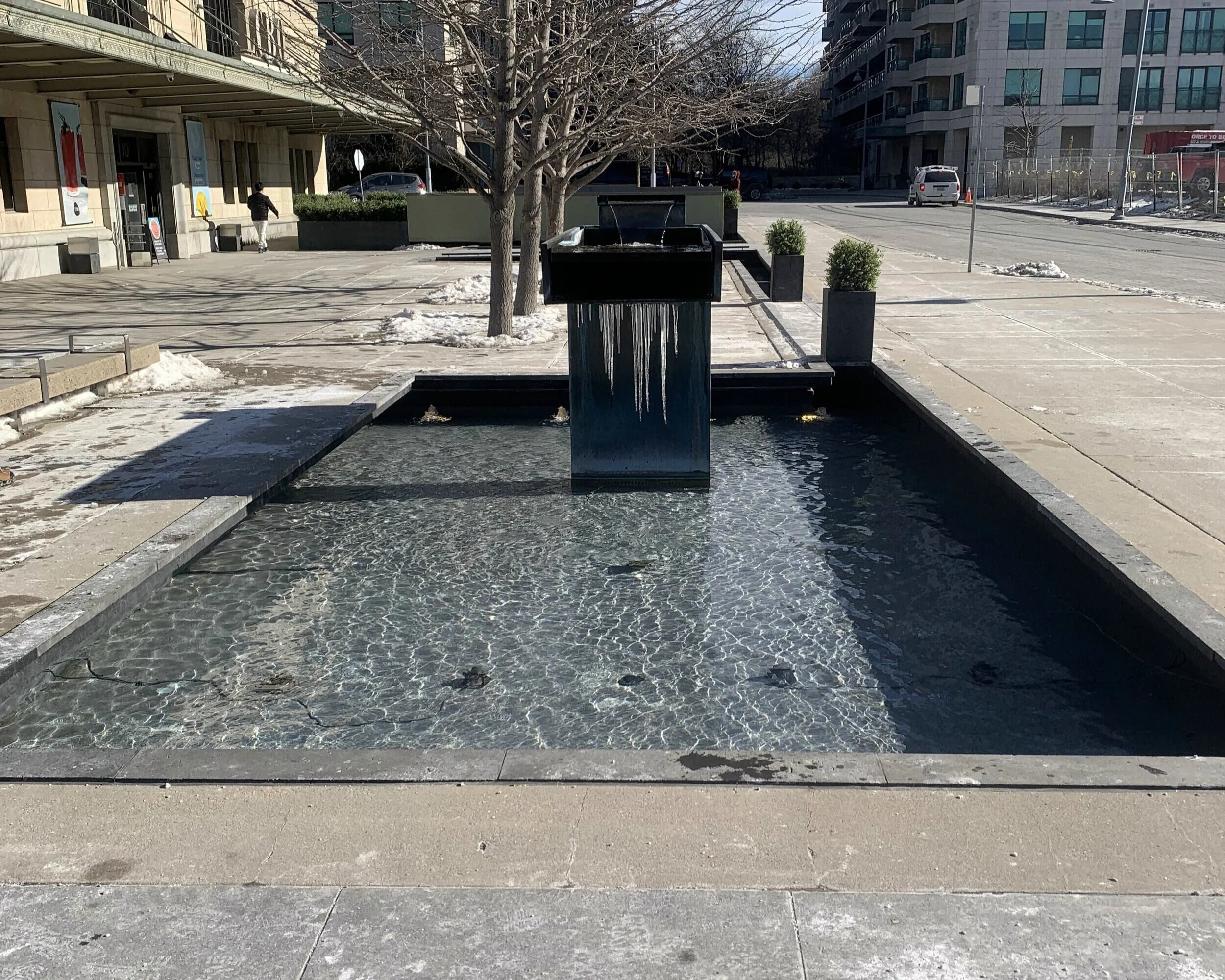 Outdoor fountain water feature installed on a public property, providing an architectural focal point within the surrounding landscape.