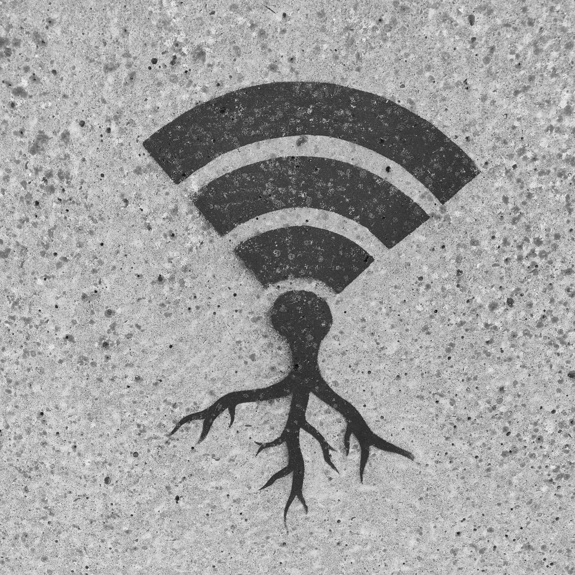 A black Wi-Fi symbol painted on a concrete pavement surface.