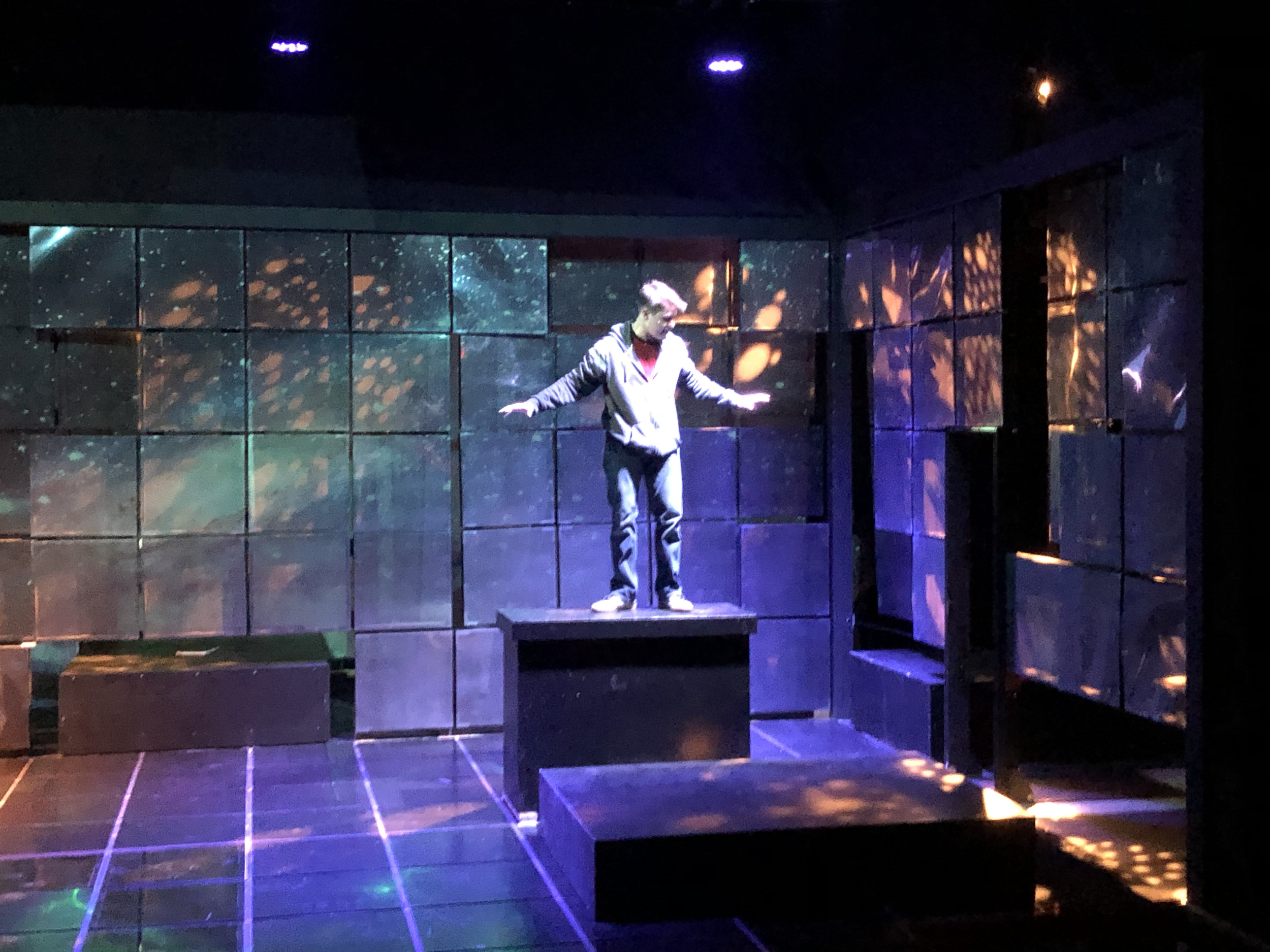 Prod. photo: Christopher in space, his safe place.  The walls have begun to fracture. The light breaks through the walls. Projections give us locations.