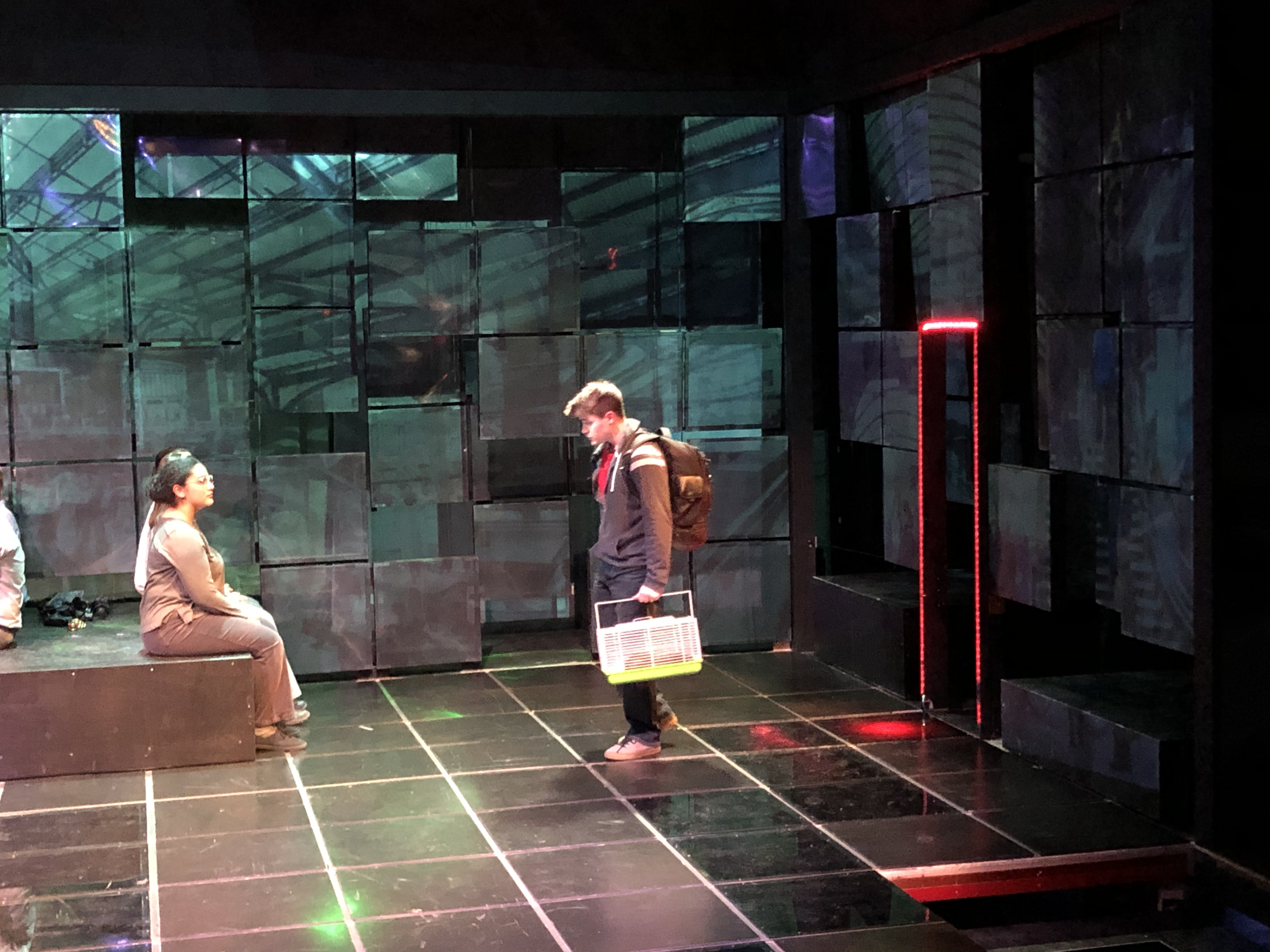 At the train station.  The floor and Doorways illuminated in red to create a pathway as Christophers recites the directions. He is trying to drown out the noise and chaos of the station