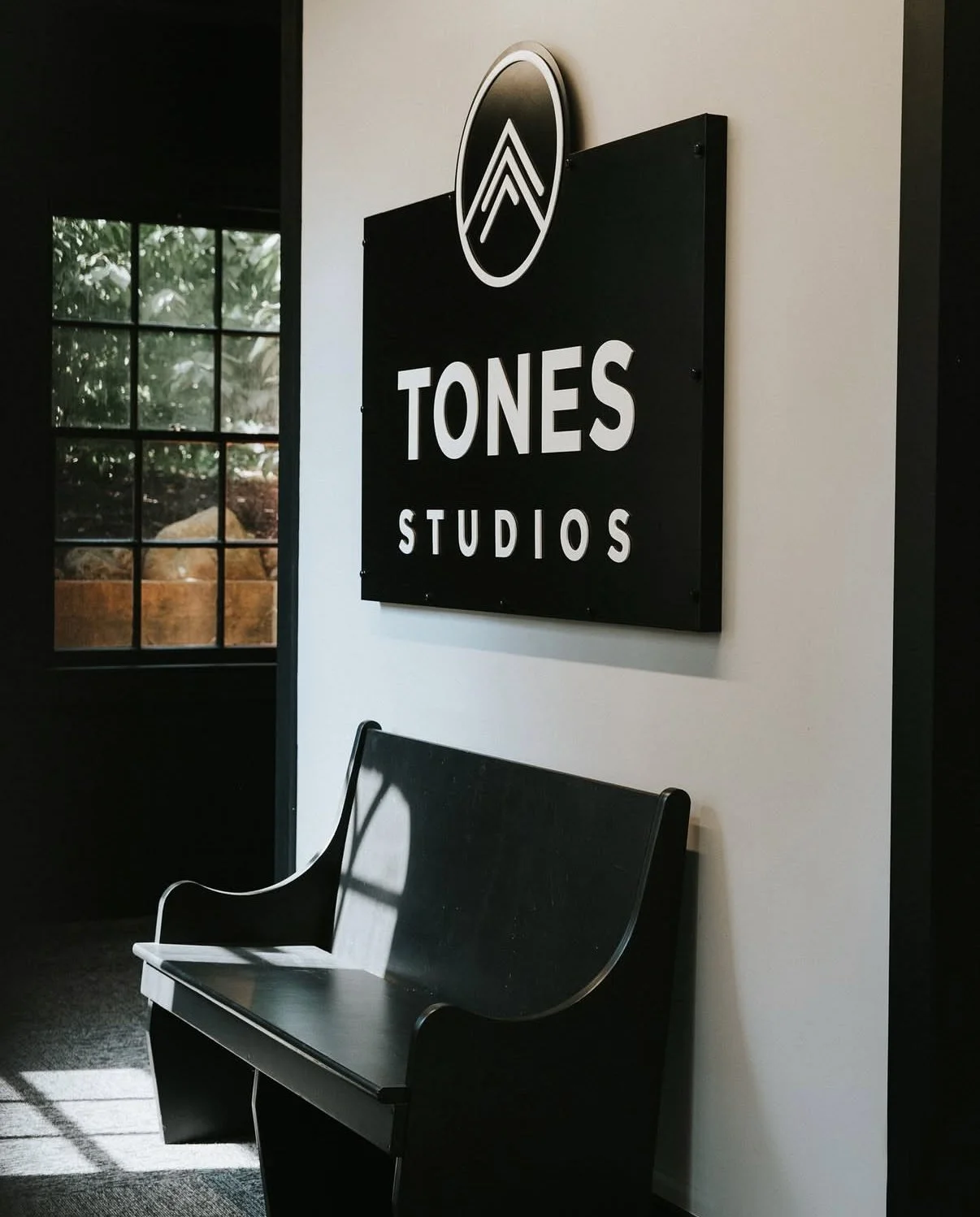 Interior of Tones Studios with a black bench and a wall sign displaying the studio's name.