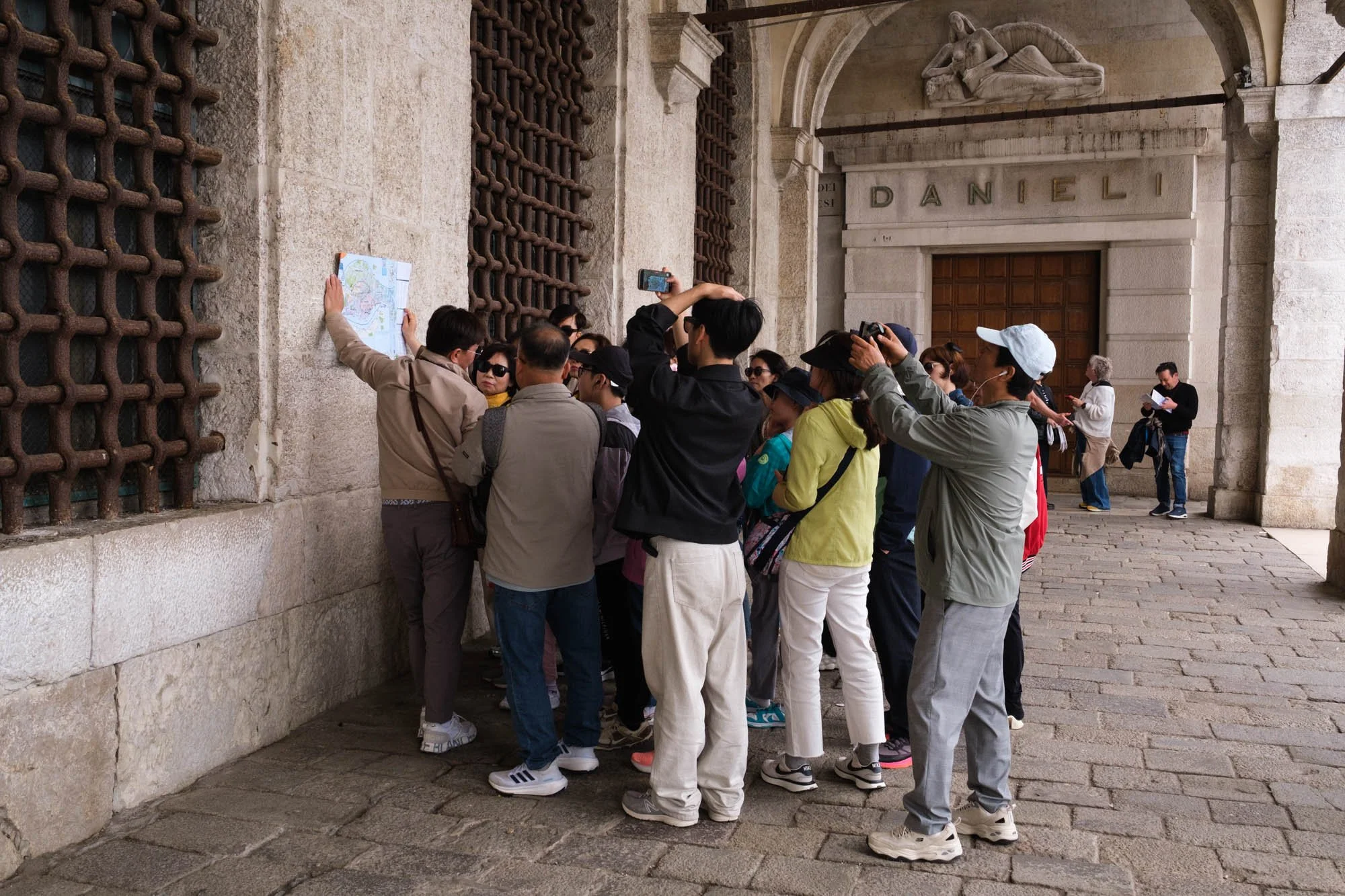 Gruppo di turisti radunati intorno a una mappa davanti all'Hotel Danieli, Venezia