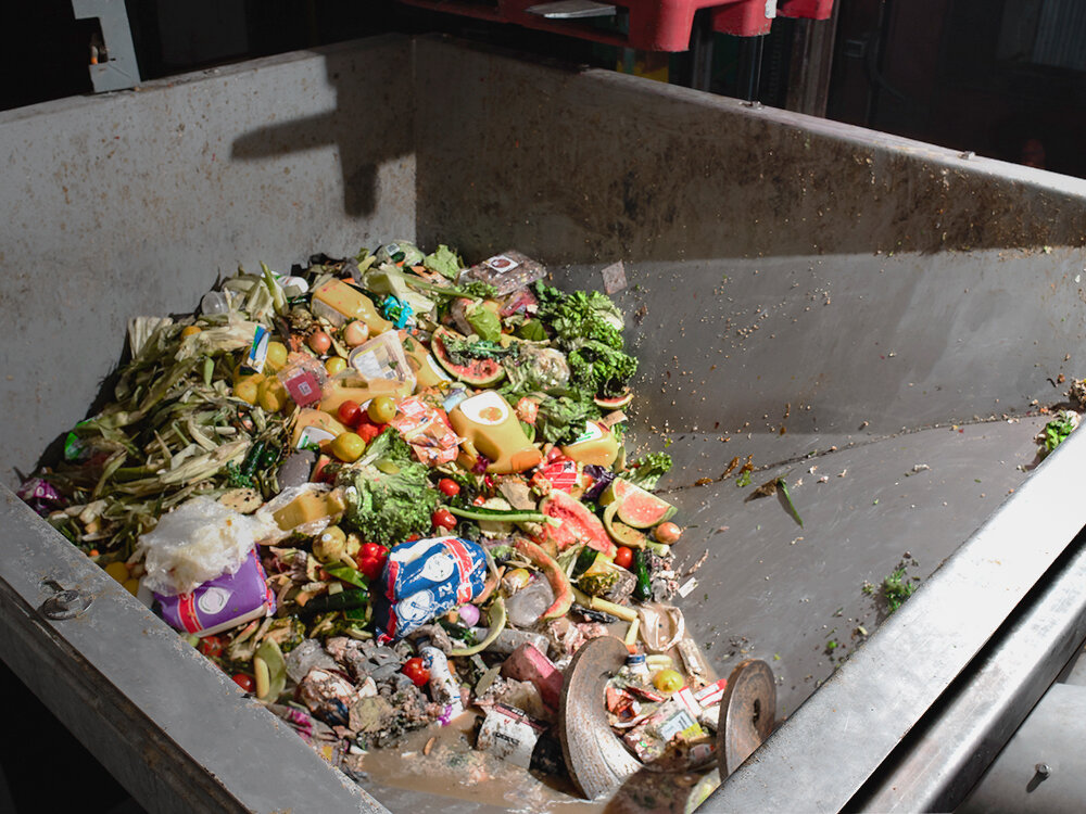 metal bin filled with food waste boxes and cans for processing