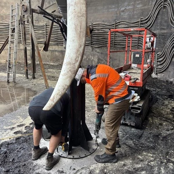 Men installing a floor mount for an agitator inside a digester tank.