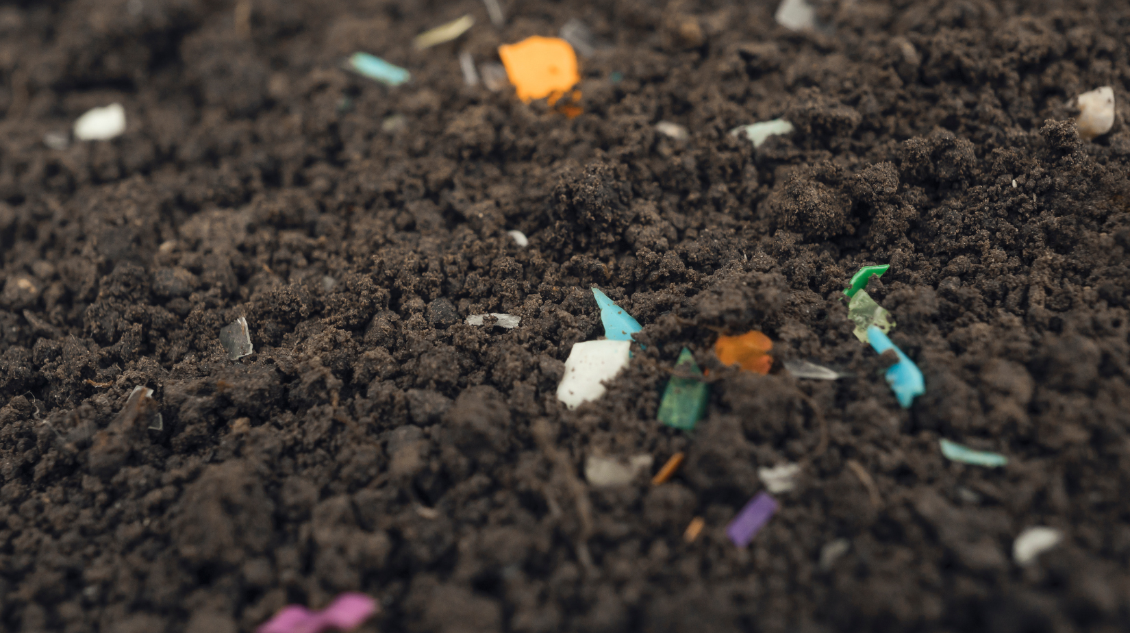 close up of soil with small bits of colored plastic mixed in