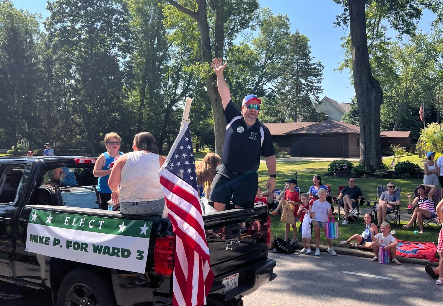 Political candidate waves to the parade crowd from his pickup truck adorned with campaign promo banners (designed & printed by Woodshed Creative.)