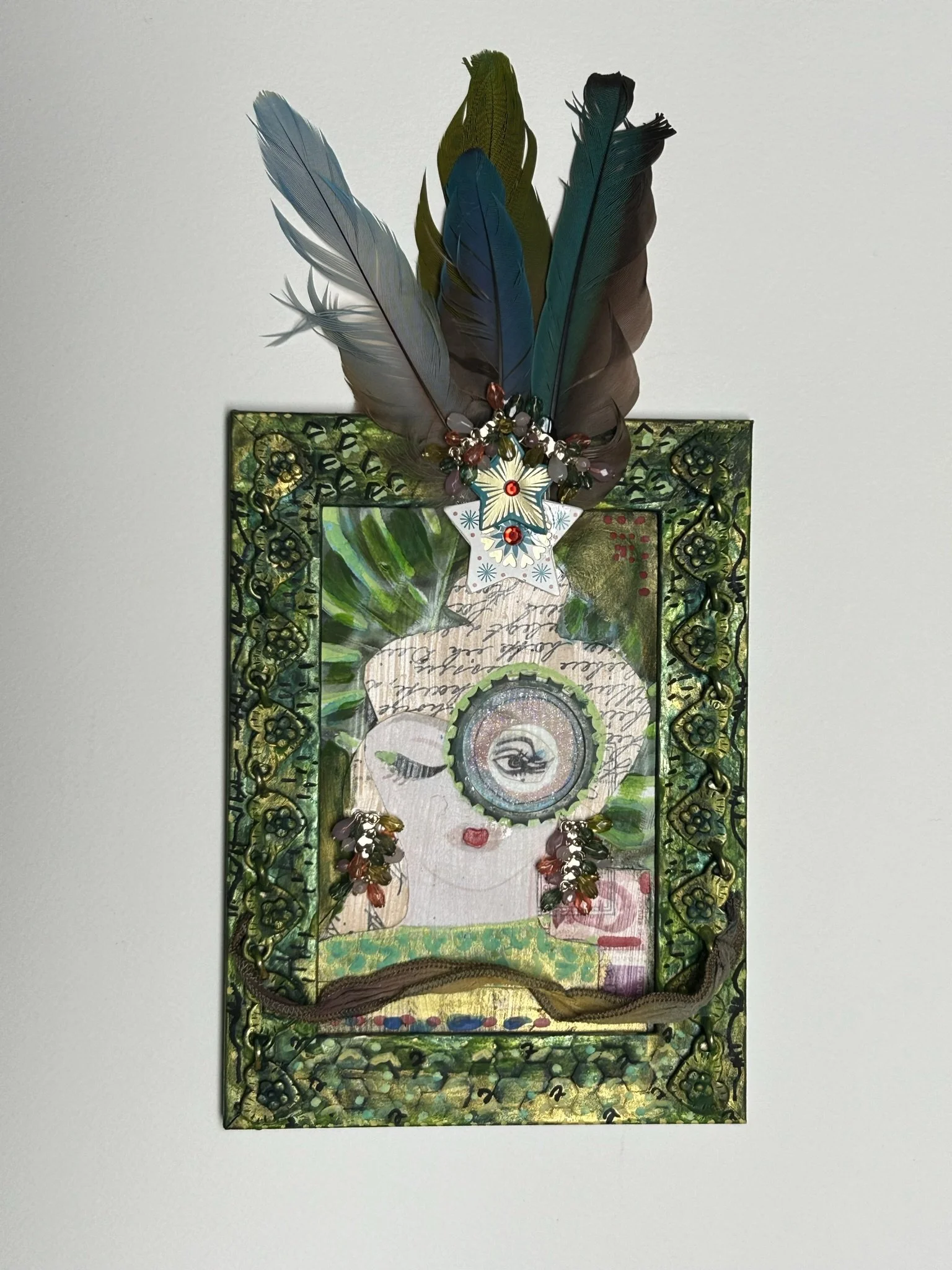 Stephanie Zing; info@bohemianartcafe.com; Assemblage--collage, acrylic paint, ink, found objects, textiles, feathers, clay; 9" x 7"; Queen of the Jungle; 400; Queen of the Jungle explores the powerful, mysterious persona that can exist beneath a fami