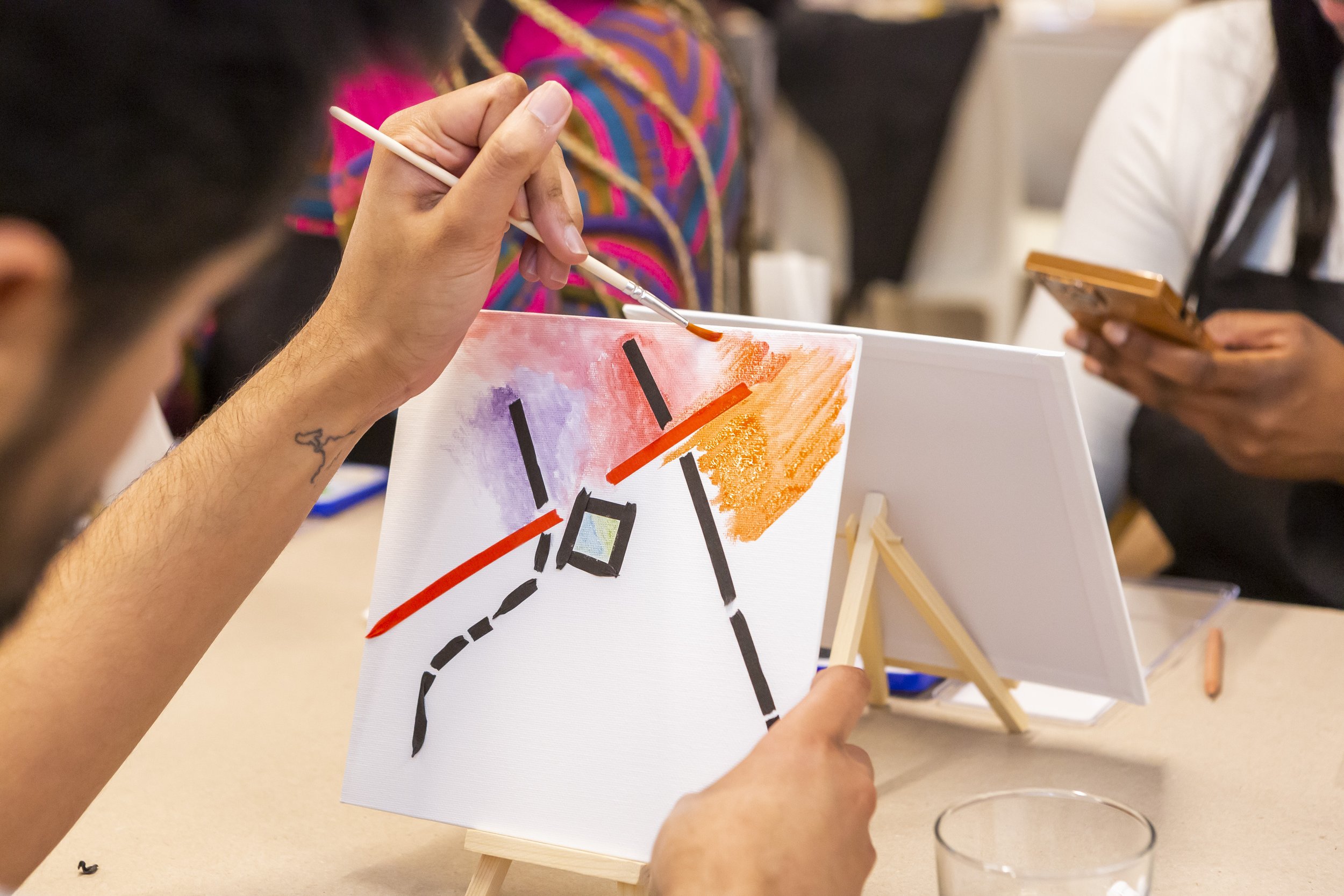 Person painting abstract art on canvas at an Art Therapy workshop.
