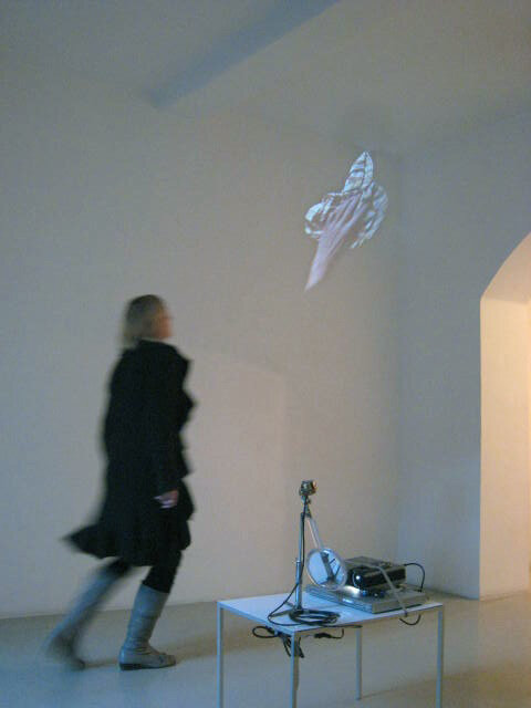 6.	Flying Mirror: cleaning cloth, 2009, slide installation with a turning handmirror, ed. 1/1, rotating motor 1 r.p.m. attached to a stative and a hand mirror, books, videoprojector PAL