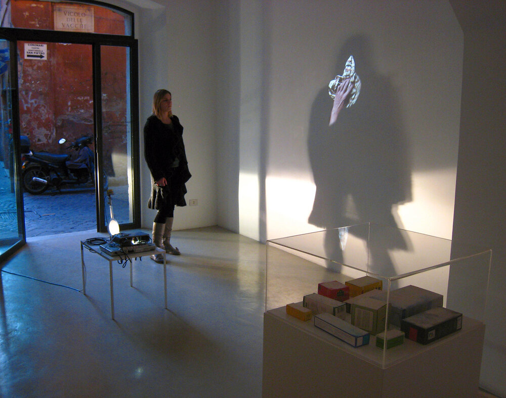 6.	Flying Mirror: cleaning cloth, 2009, slide installation with a turning handmirror, ed. 1/1, rotating motor 1 r.p.m. attached to a stative and a hand mirror, books, videoprojector PAL