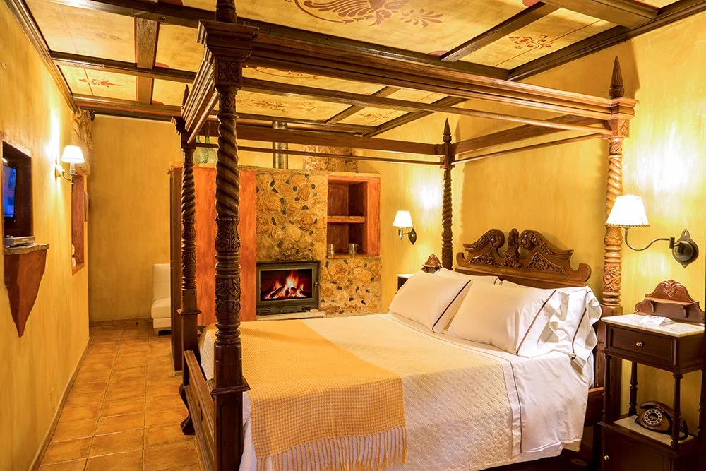 Habitación Superior Deluxe Rústica en La Casa del Rector, hotel con encanto en Almagro; estancia de 36 m² con cama con dosel, salón con chimenea, zona de lectura con vistas al estanque y bañera de piedra para dos personas.