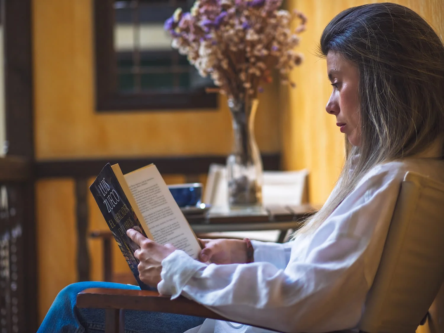 Mujer relajada leyendo y disfrutando del slow living en La Casa del Rector, hotel con spa y espacios de calma.