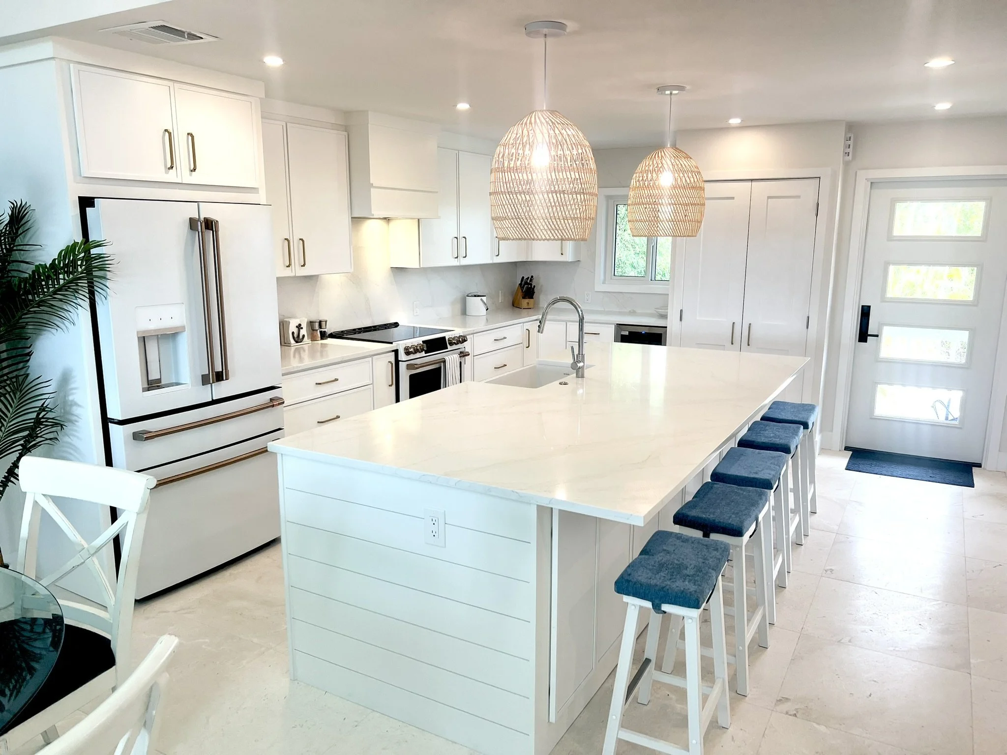 Modern white kitchen with large island, pendant lights, and stainless steel appliances