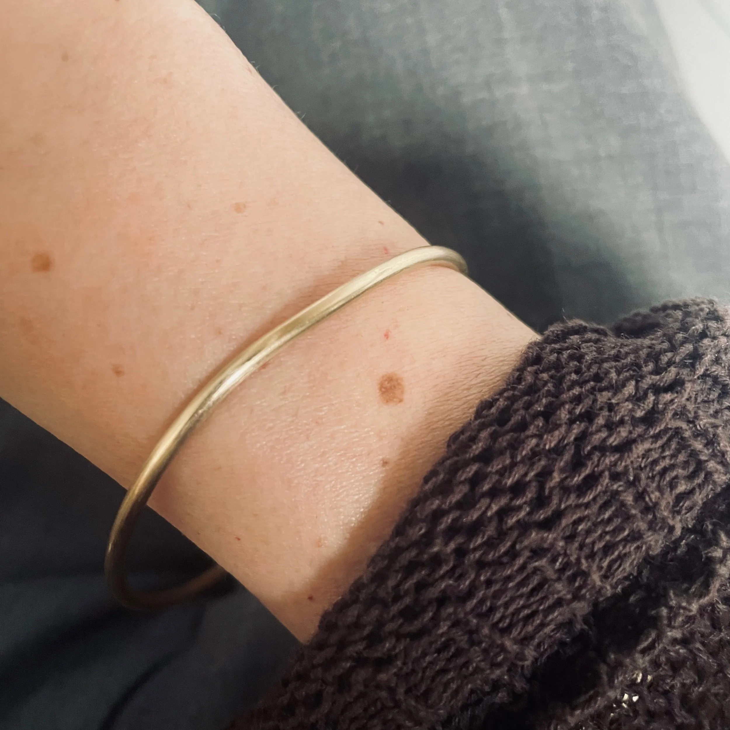 Handmade solid recycled gold bangle photographed worn