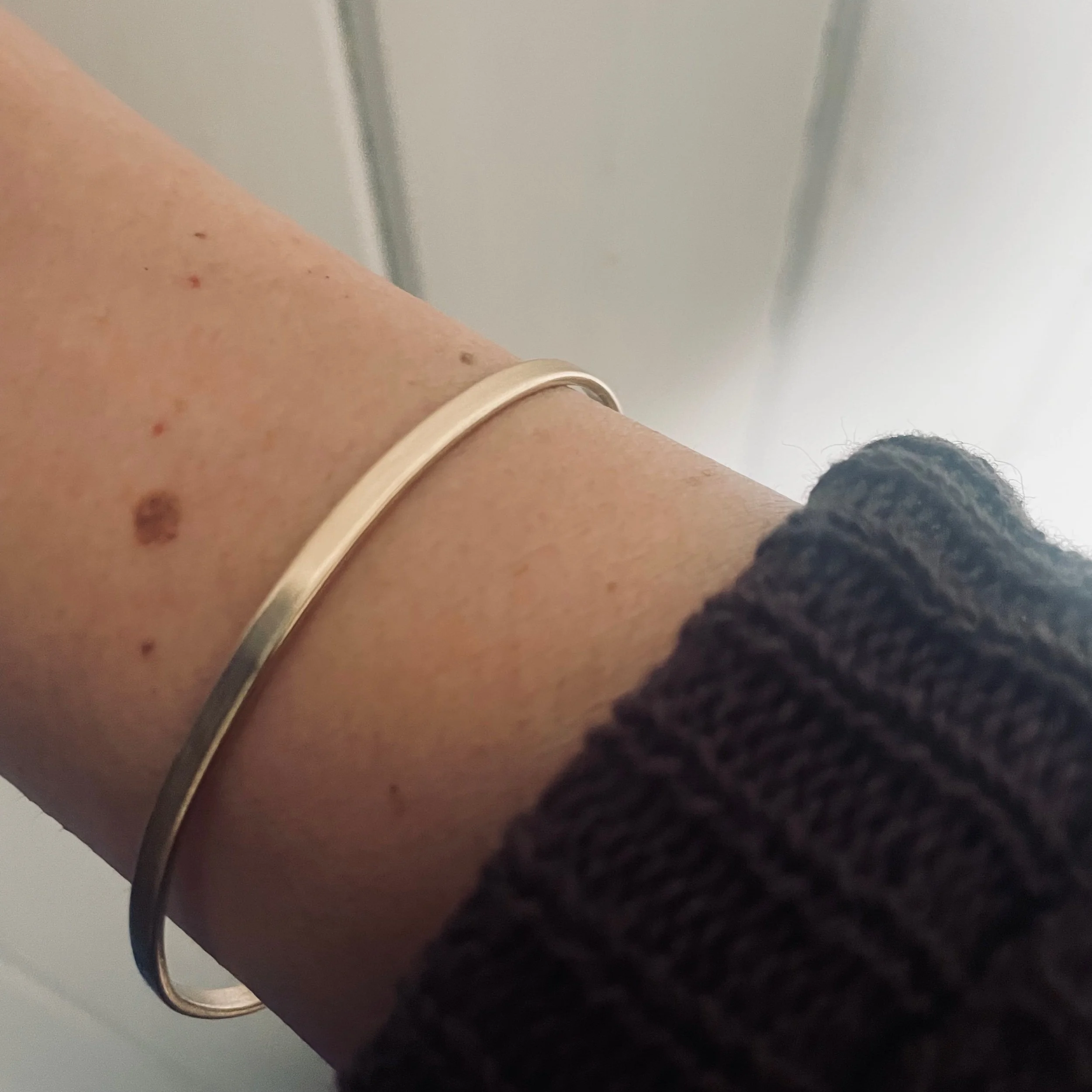 Handmade milled solid recycled gold bangle photographed worn