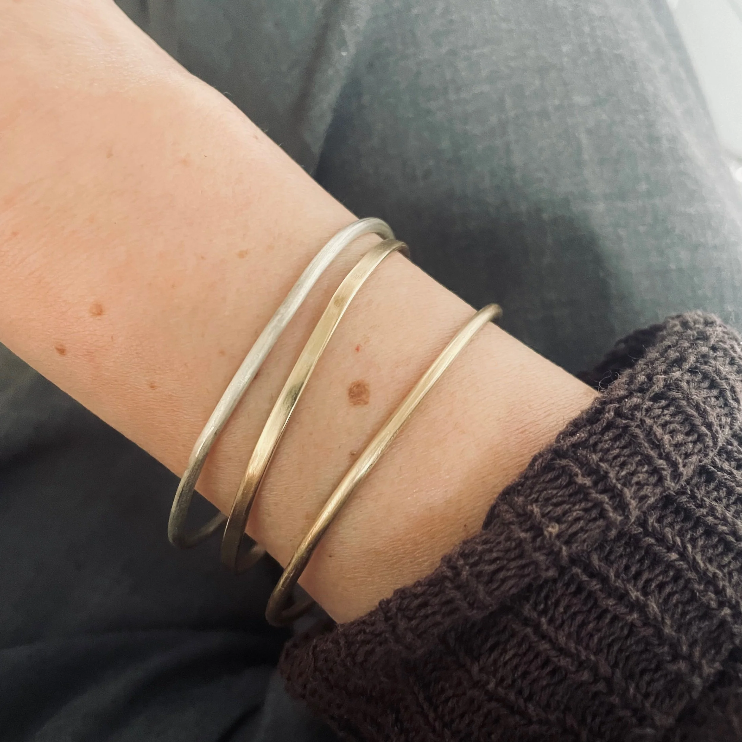 Handmade solid recycled gold and silver bangles photographed worn