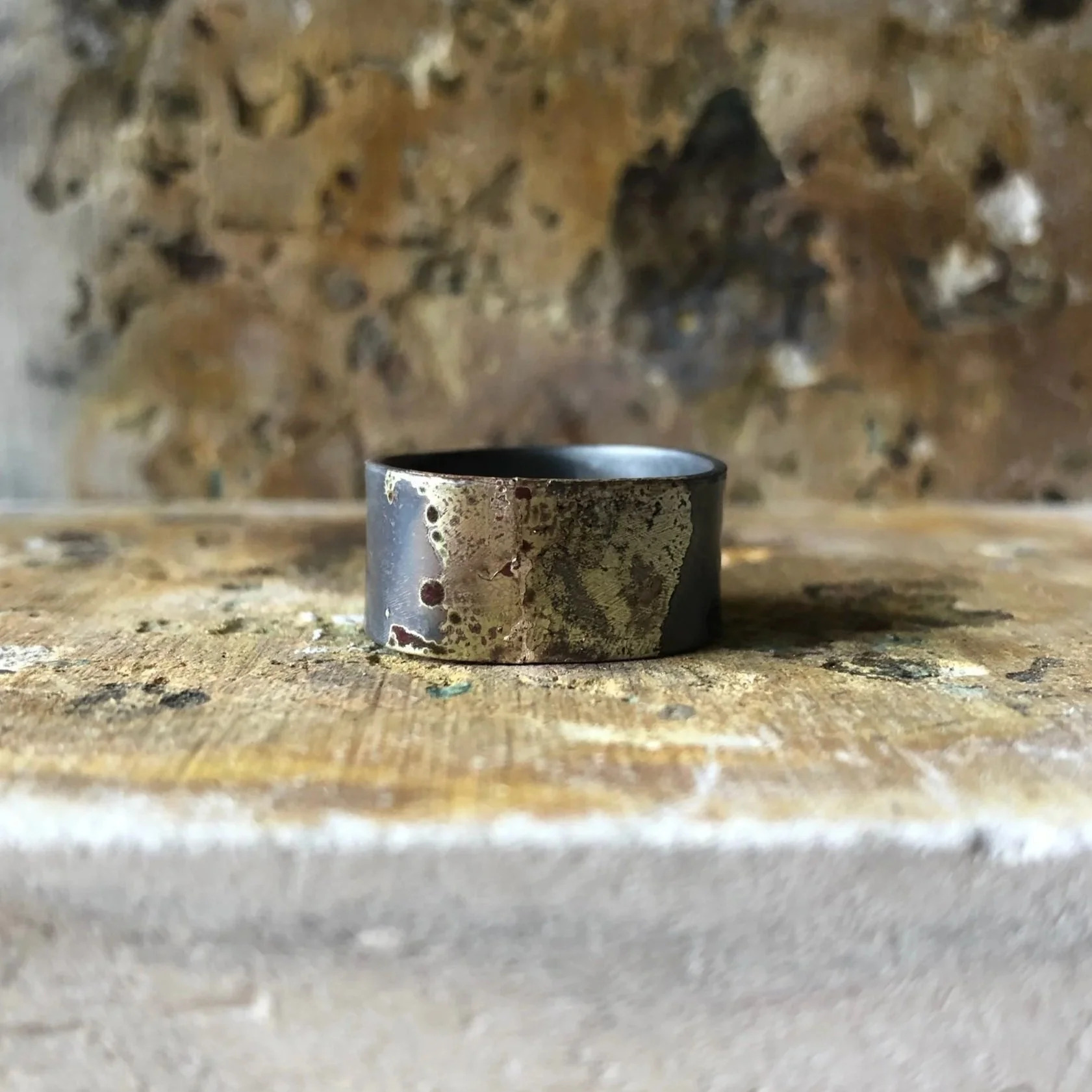 Handcrafted wide band recycled solid silver ring phtographed on textured soldering blocks just after soldering, raw