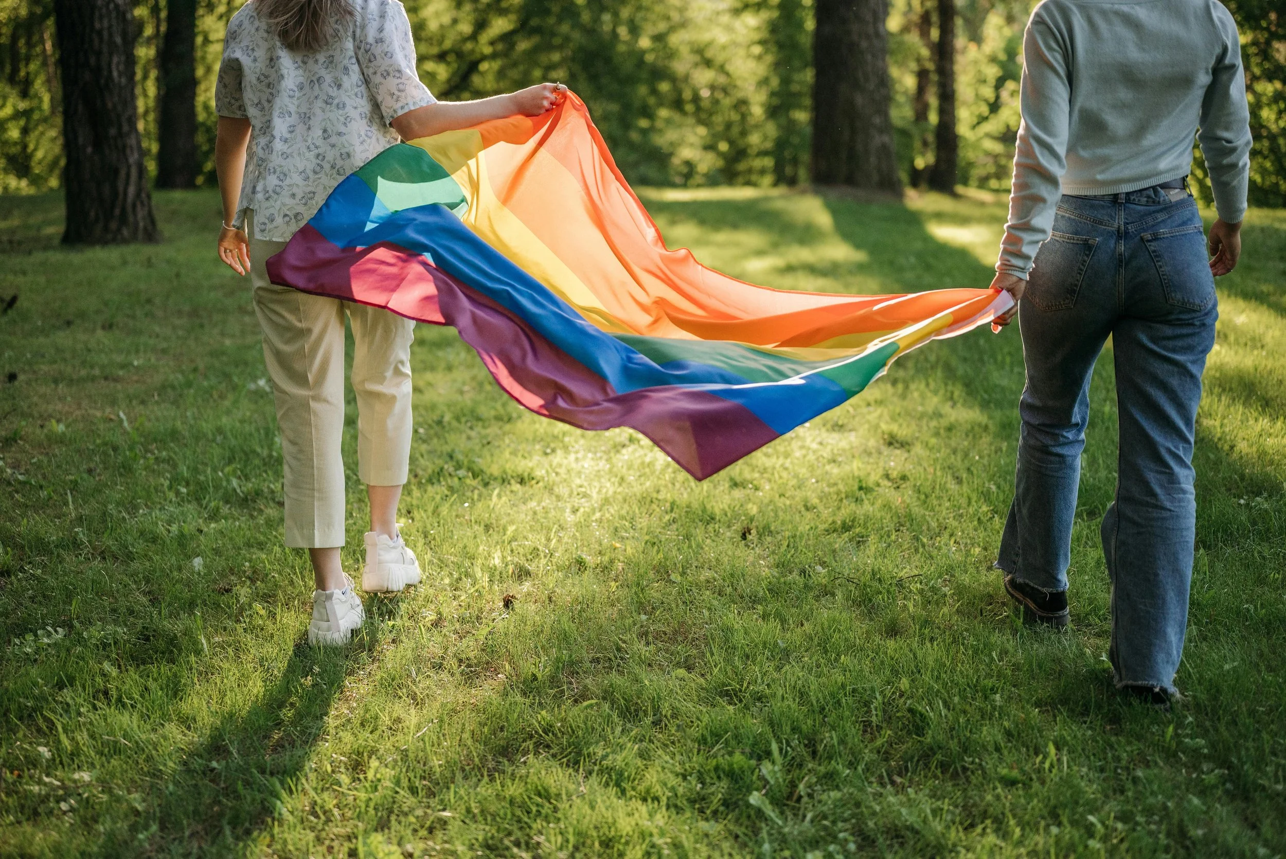 LGBTQ+ image, with two people holding a LGBTQ flag, representing connection, identity and self-expression.