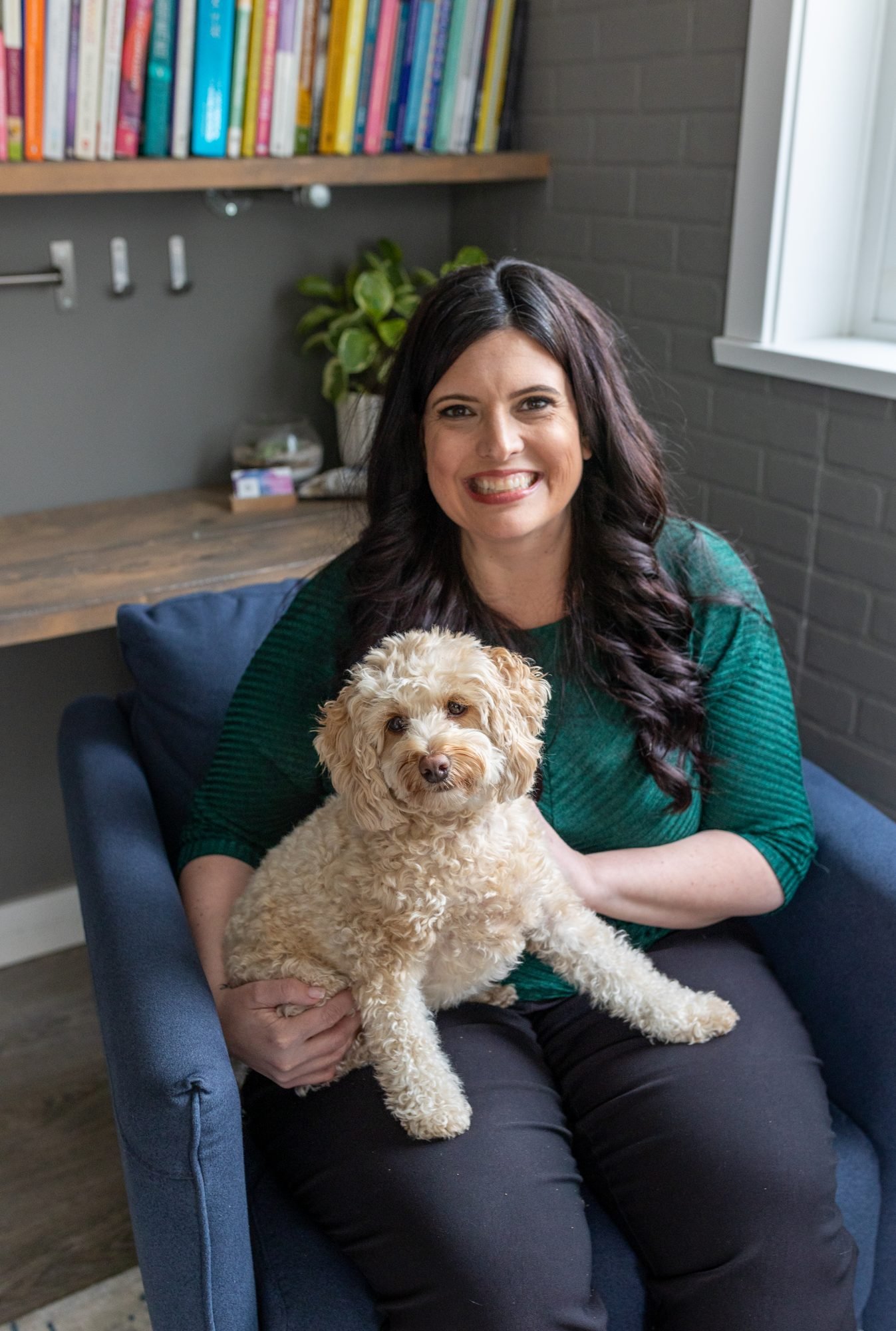 Elizabeth Nardella in her office armchair with Lyon, her fluffy cream-coloured dog