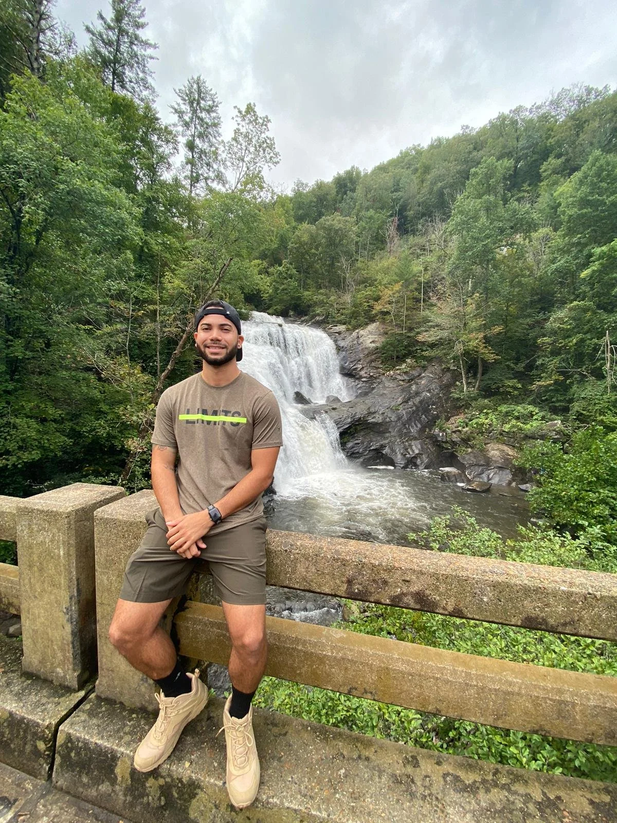 Armani smiling beside a waterfall during a mountain trip