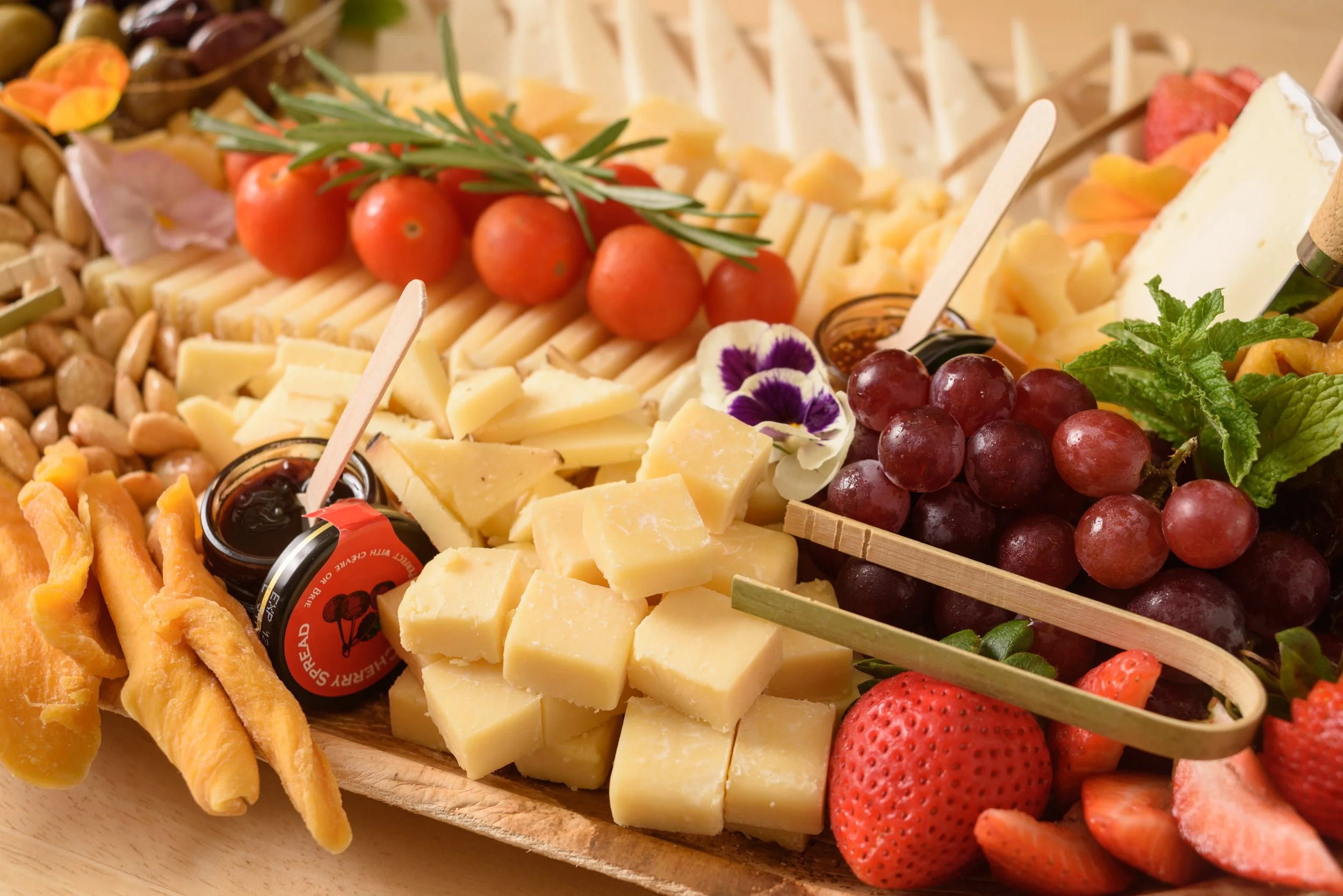 A cheese platter from the Cheese Corner in Westerly with a variety of sliced and crumbled hard and soft cheeses, charcuterie, fruits, olives, nuts, fig jam and honey. 