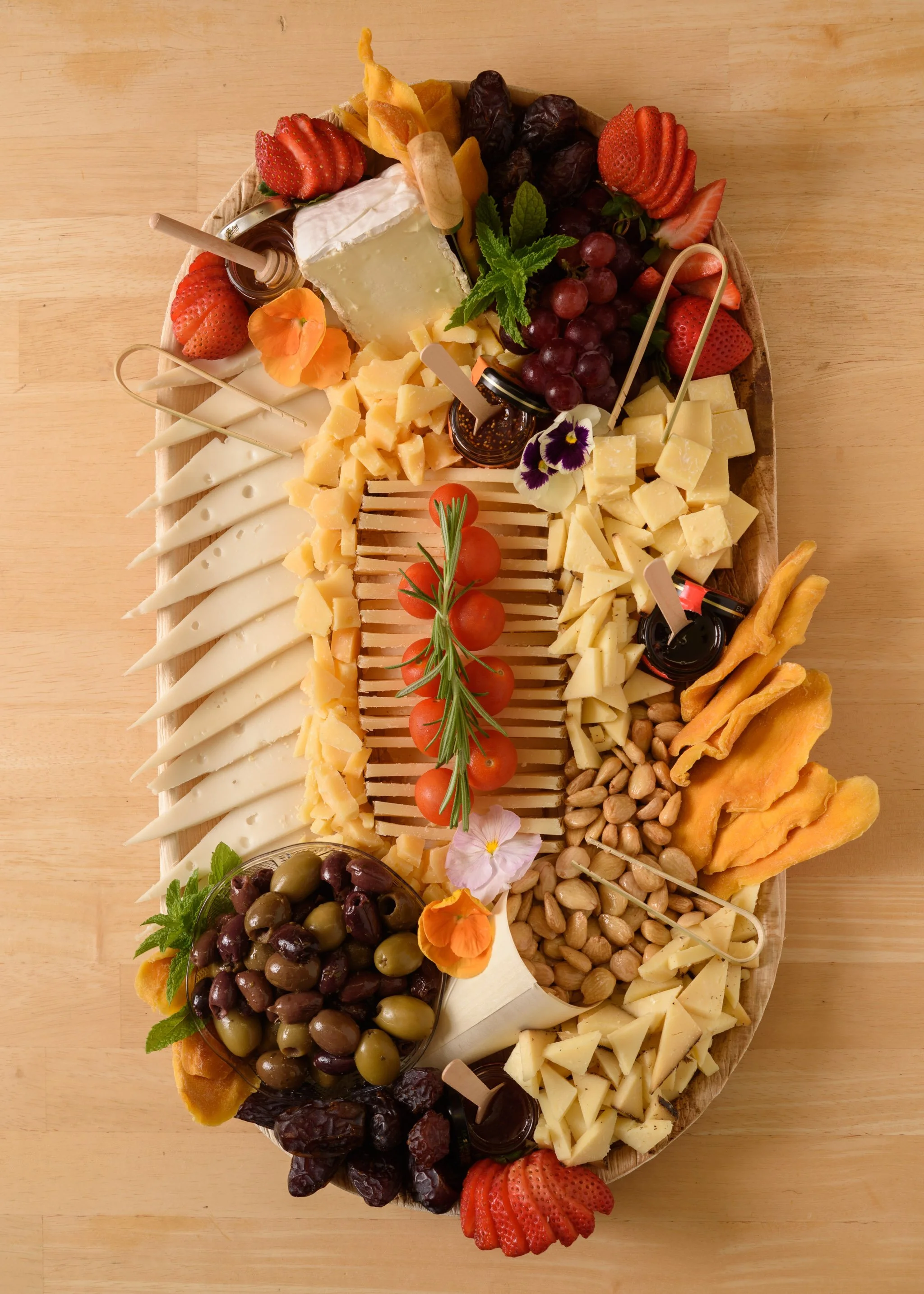 A cheese platter from the Cheese Corner in Westerly with a variety of sliced and crumbled hard and soft cheeses, charcuterie, fruits, olives, nuts, fig jam and honey. 