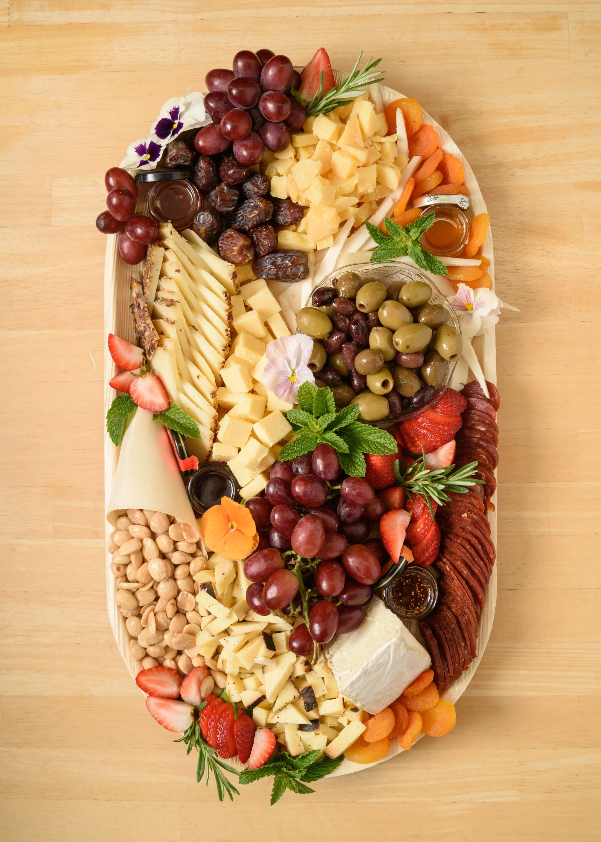 A cheese platter from the Cheese Corner in Westerly with a variety of sliced and crumbled hard and soft cheeses, charcuterie, fruits, olives, nuts, fig jam and honey. 