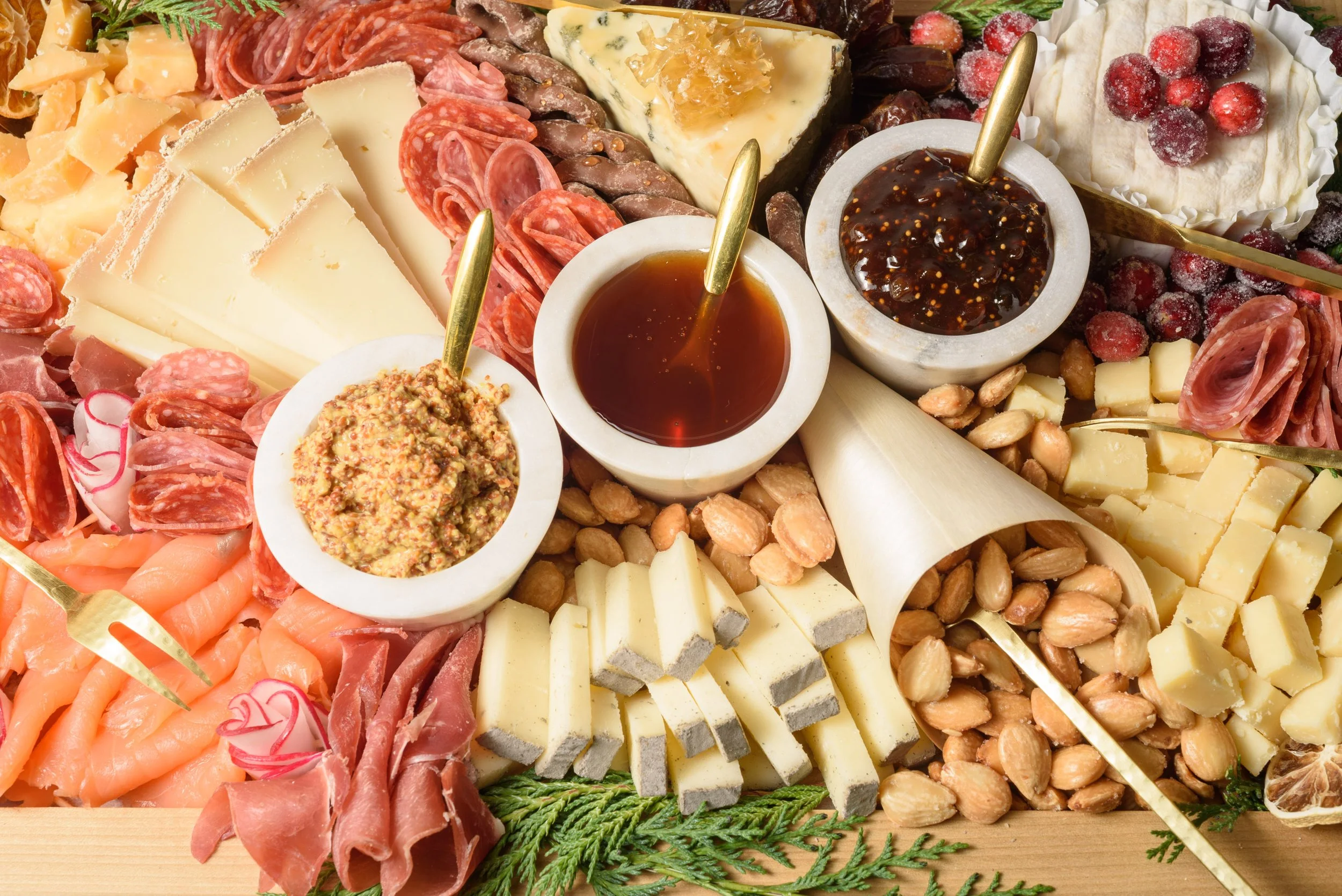 A cheese platter from the Cheese Corner in Westerly with a variety of sliced and crumbled hard and soft cheeses, charcuterie, fruits, olives, nuts, fig jam and honey. 