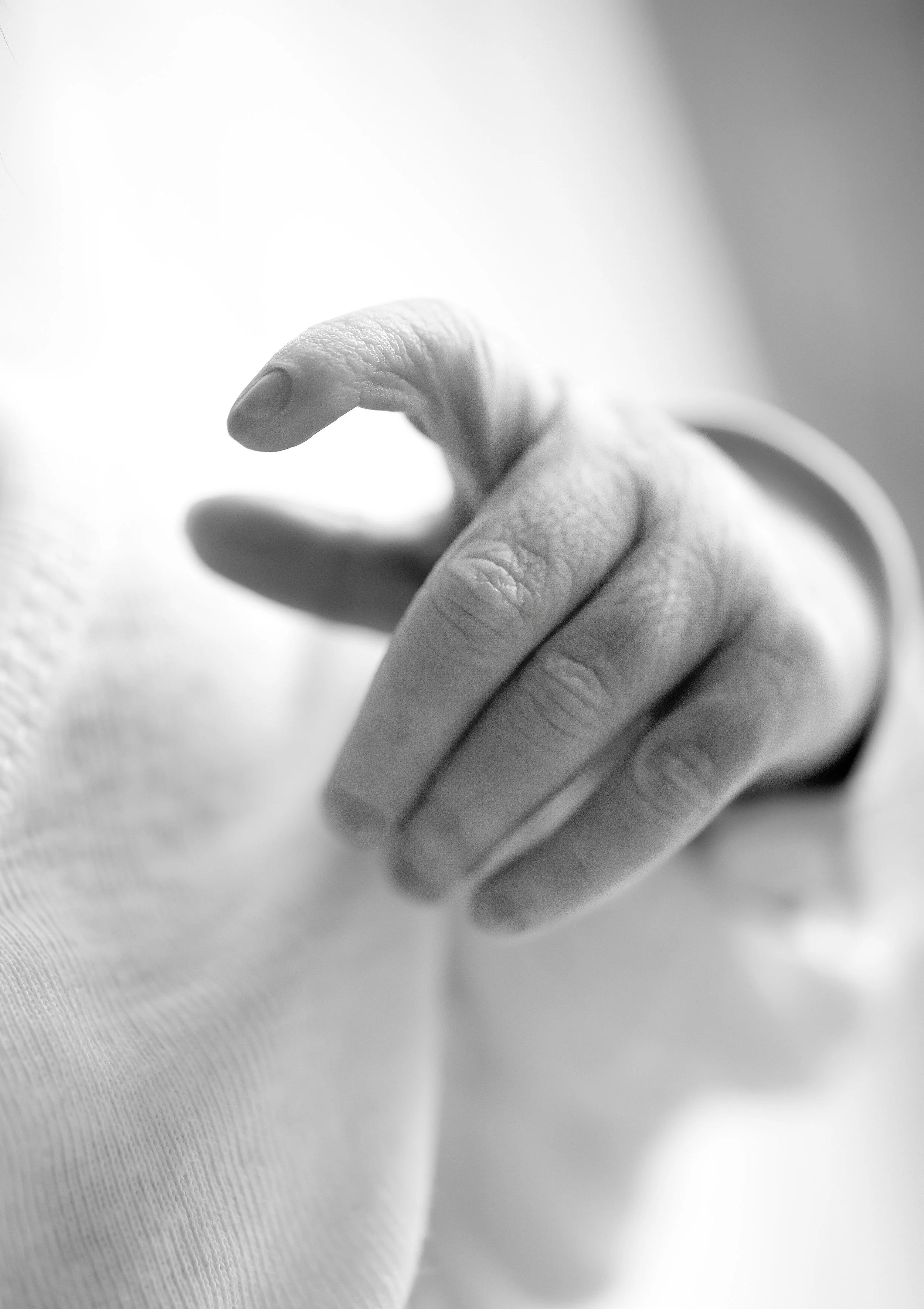Close-up of a newborn's moving hand, with a focus on the fingers and thumb.