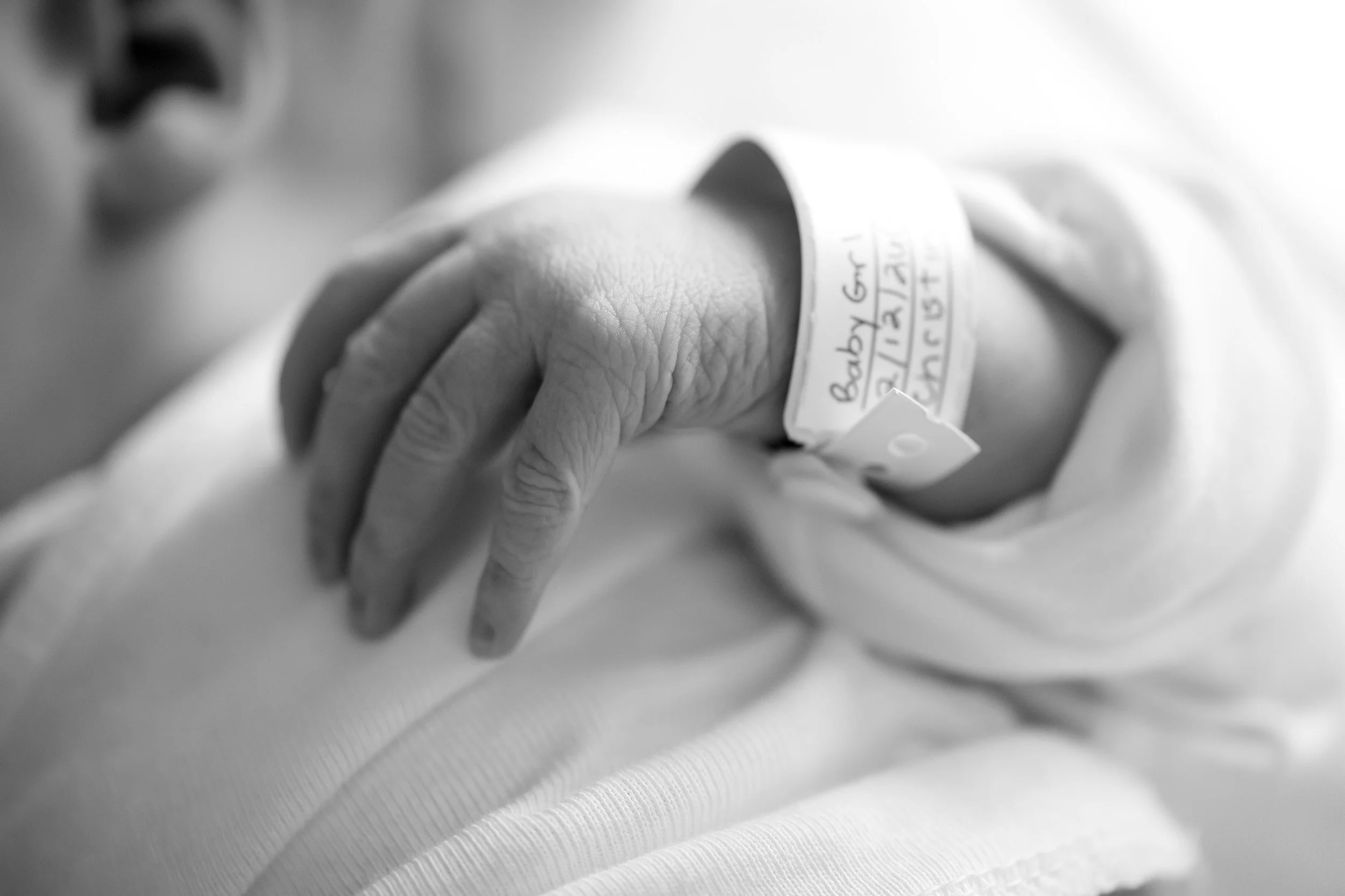 Close-up of a person's hand with medical identification bracelet in a hospital setting.
