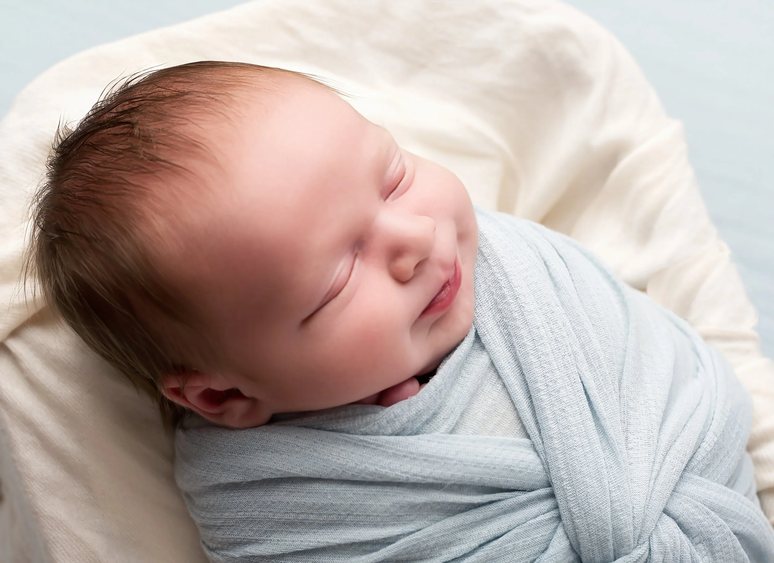 Close-up of a sleeping newborn baby wrapped in a soft blanket